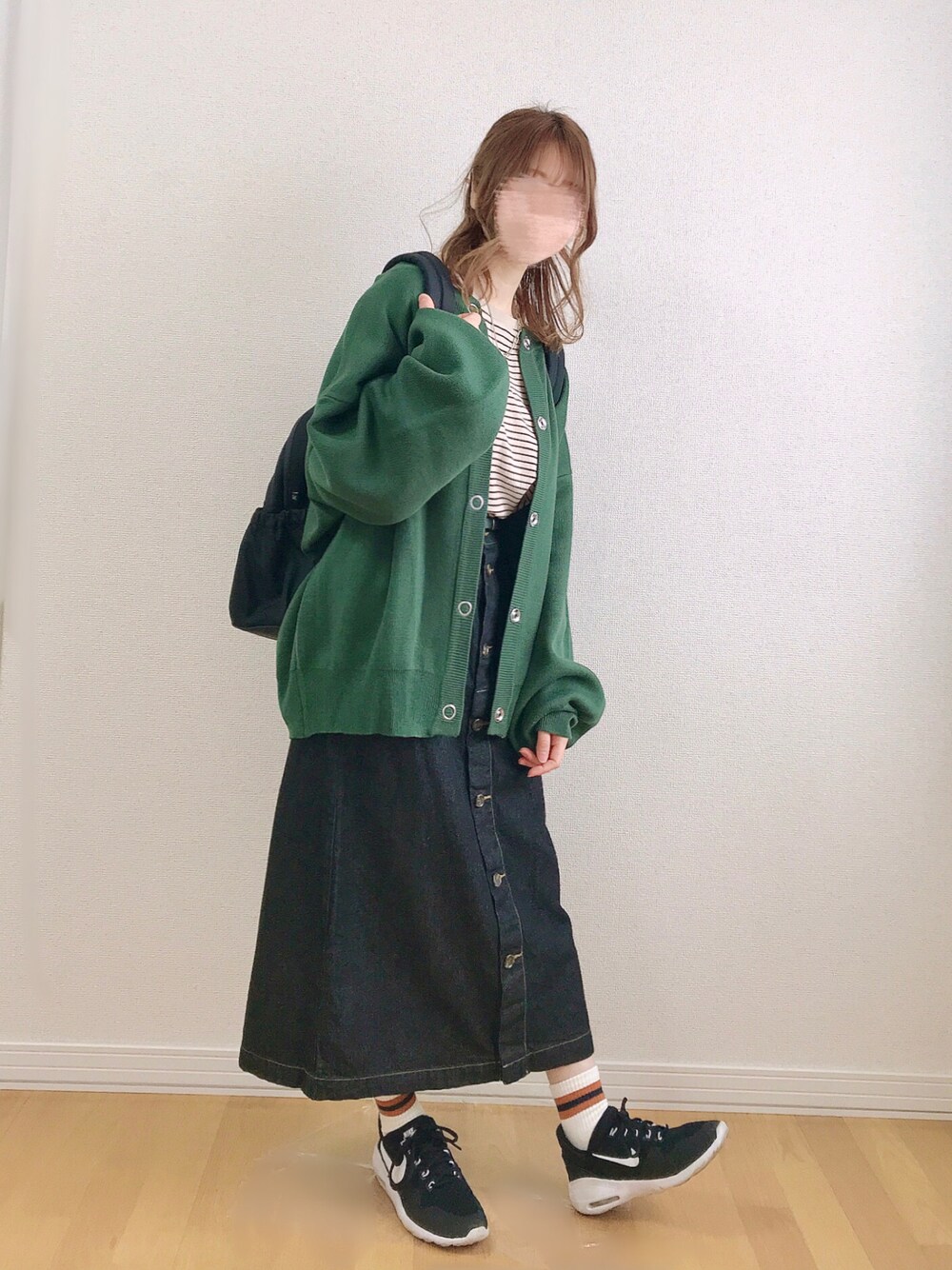 グリーン系のカーディガン/ボレロ、ベージュ系のTシャツ/カットソー、ブラック系のスカートを着用したレディースの春コーディネートの1枚目の写真