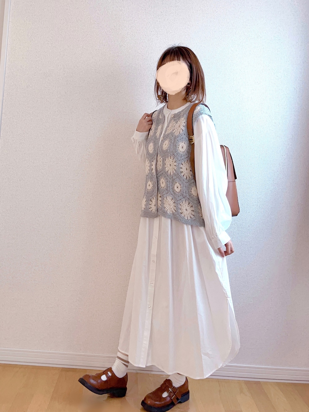 グレー系のベスト、ホワイト系のワンピース、イエロー系のバックパック/リュックを着用したレディースの秋コーディネートの1枚目の写真