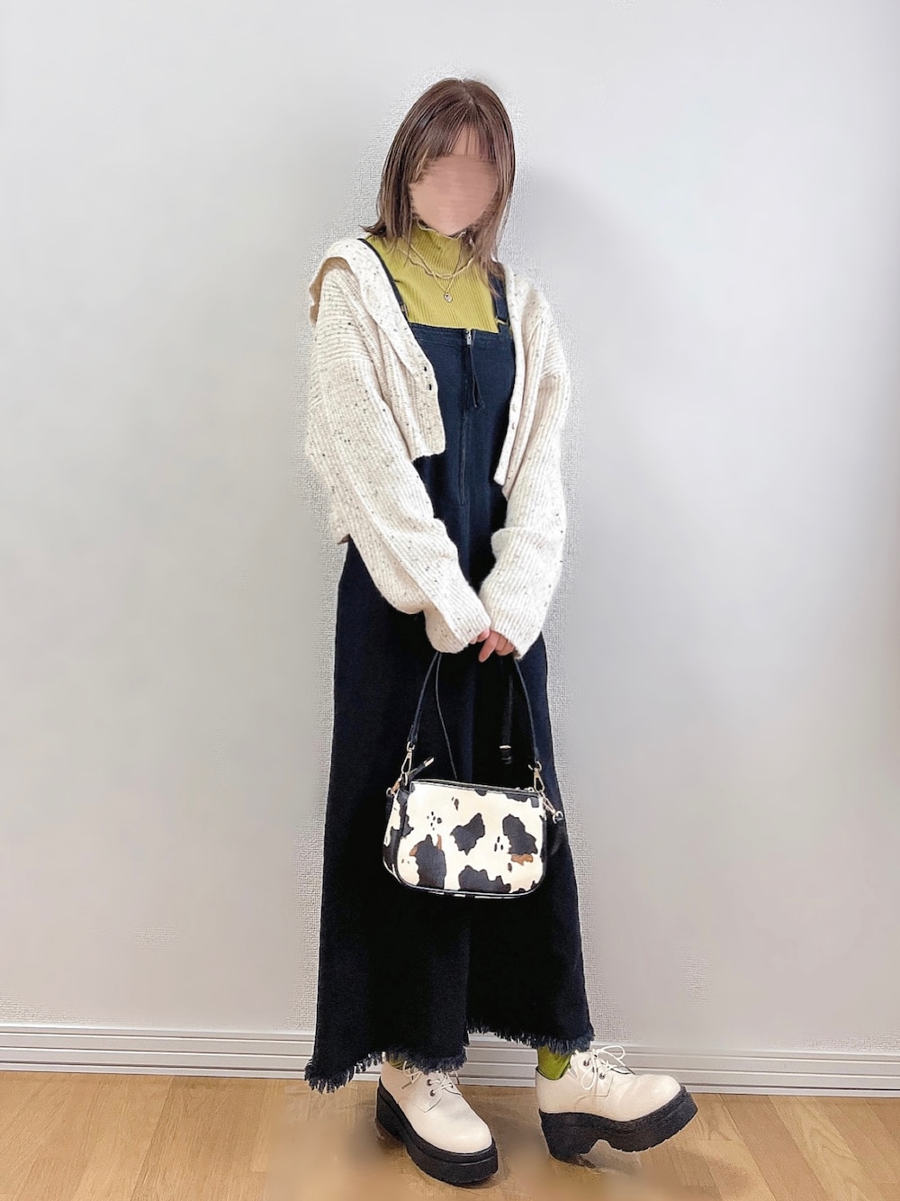 ブラック系のジャンパースカート、ホワイト系のカーディガン/ボレロ、イエロー系のTシャツ/カットソーを着用したレディースの秋コーディネートの1枚目の写真