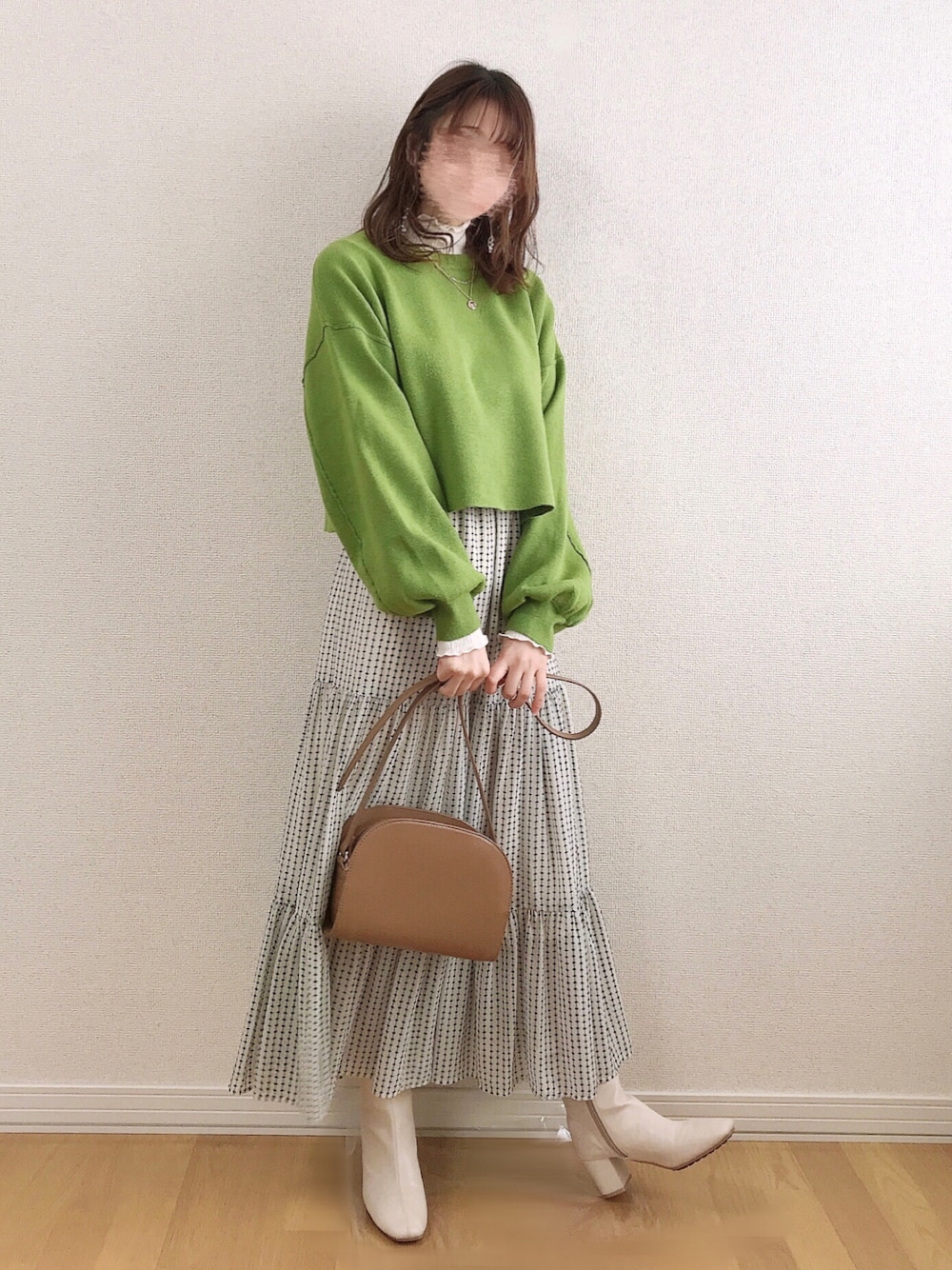 グリーン系のニット/セーター、ホワイト系のTシャツ/カットソー、ホワイト系のスカートを着用したレディースの冬コーディネートの1枚目の写真