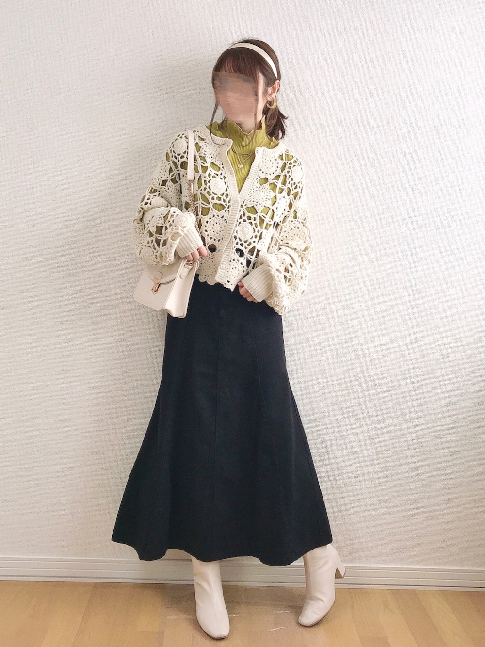 ホワイト系のカーディガン/ボレロ、イエロー系のTシャツ/カットソー、ブラック系のデニムスカートを着用したレディースの冬コーディネートの1枚目の写真