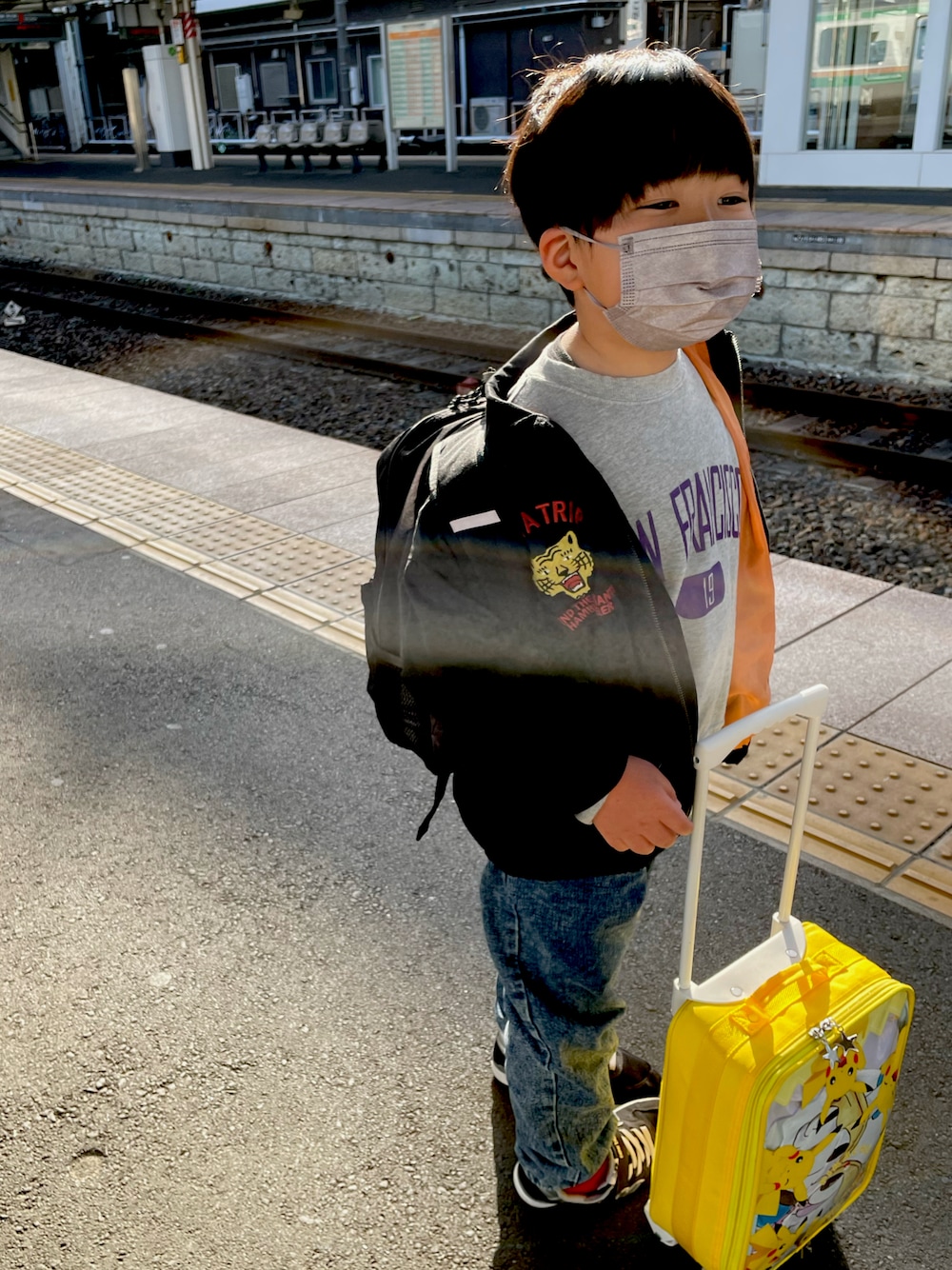 イエロー系のスーツケース/キャリーバッグ、ブラック系のその他アウター、グレー系のスウェットを着用したキッズの春コーディネートの1枚目の写真