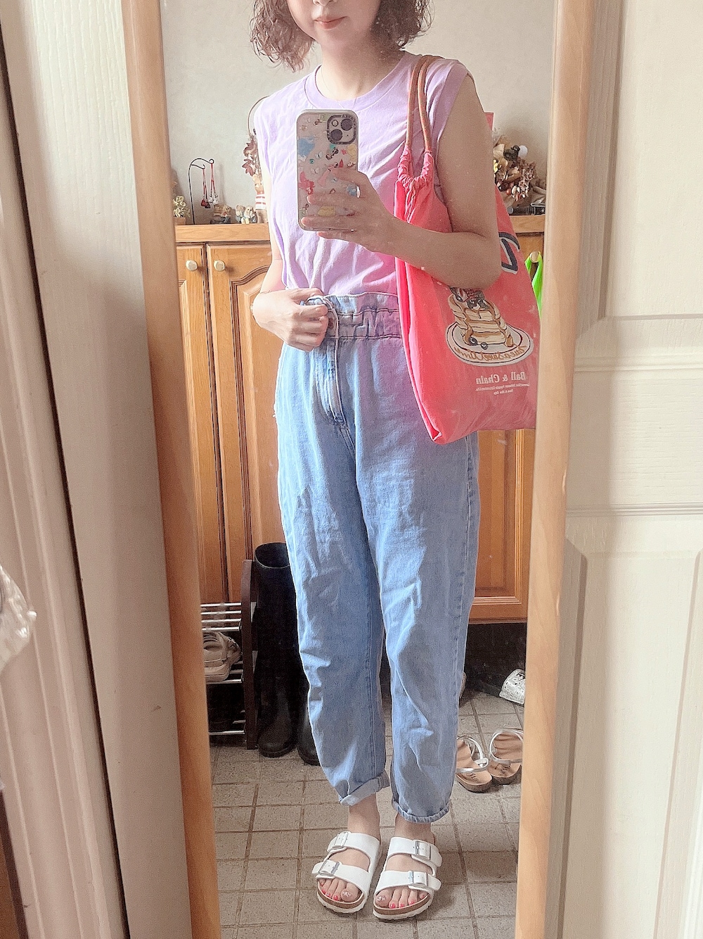 ピンク系のタンクトップ、ピンク系のバッグ、ブルー系のデニムパンツを着用したレディースの夏コーディネートの1枚目の写真