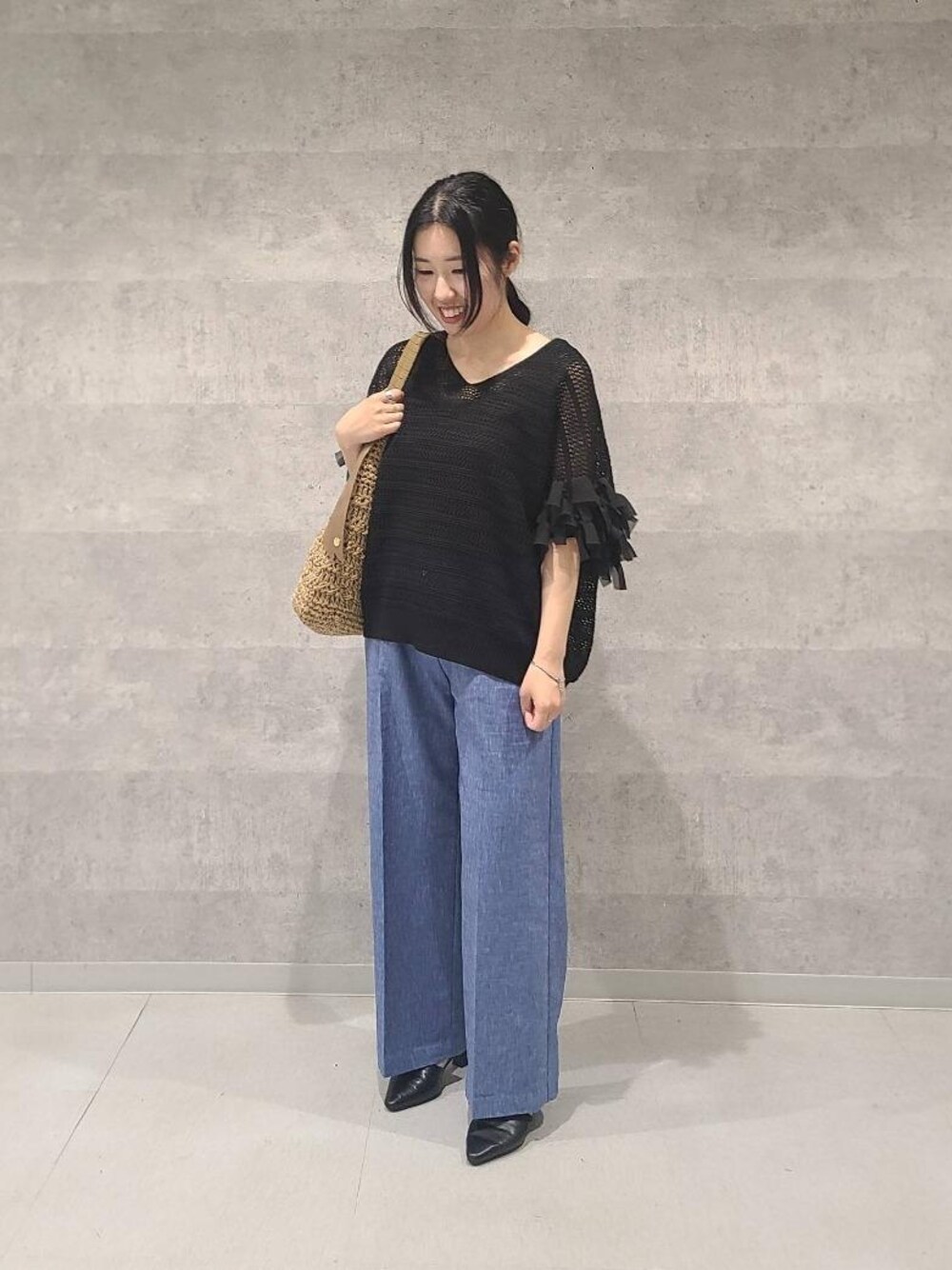 ブルー系のその他パンツ、ブラック系のトートバッグ、ブラック系のニット/セーターを着用したレディースの春コーディネートの1枚目の写真