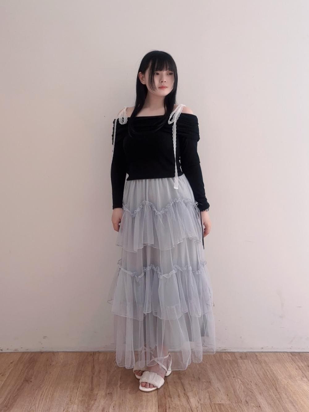ブラック系のTシャツ/カットソー、グレー系のスカート、ホワイト系のサンダルを着用したレディースの春コーディネートの1枚目の写真