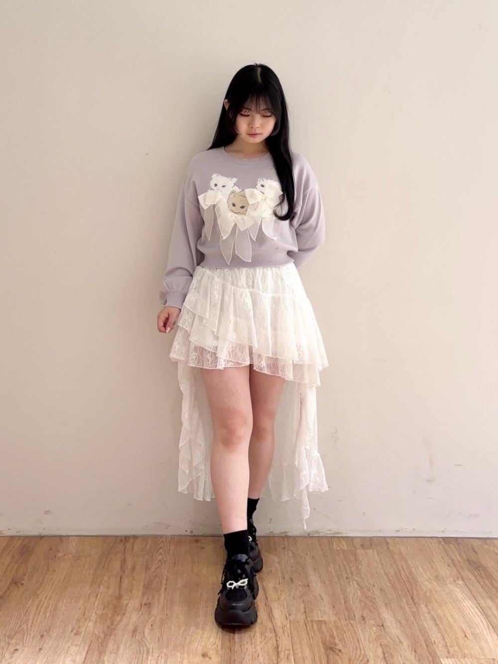 ブラック系のスニーカー、ホワイト系のスカート、グレー系のニット/セーターを着用したレディースの冬コーディネートの1枚目の写真