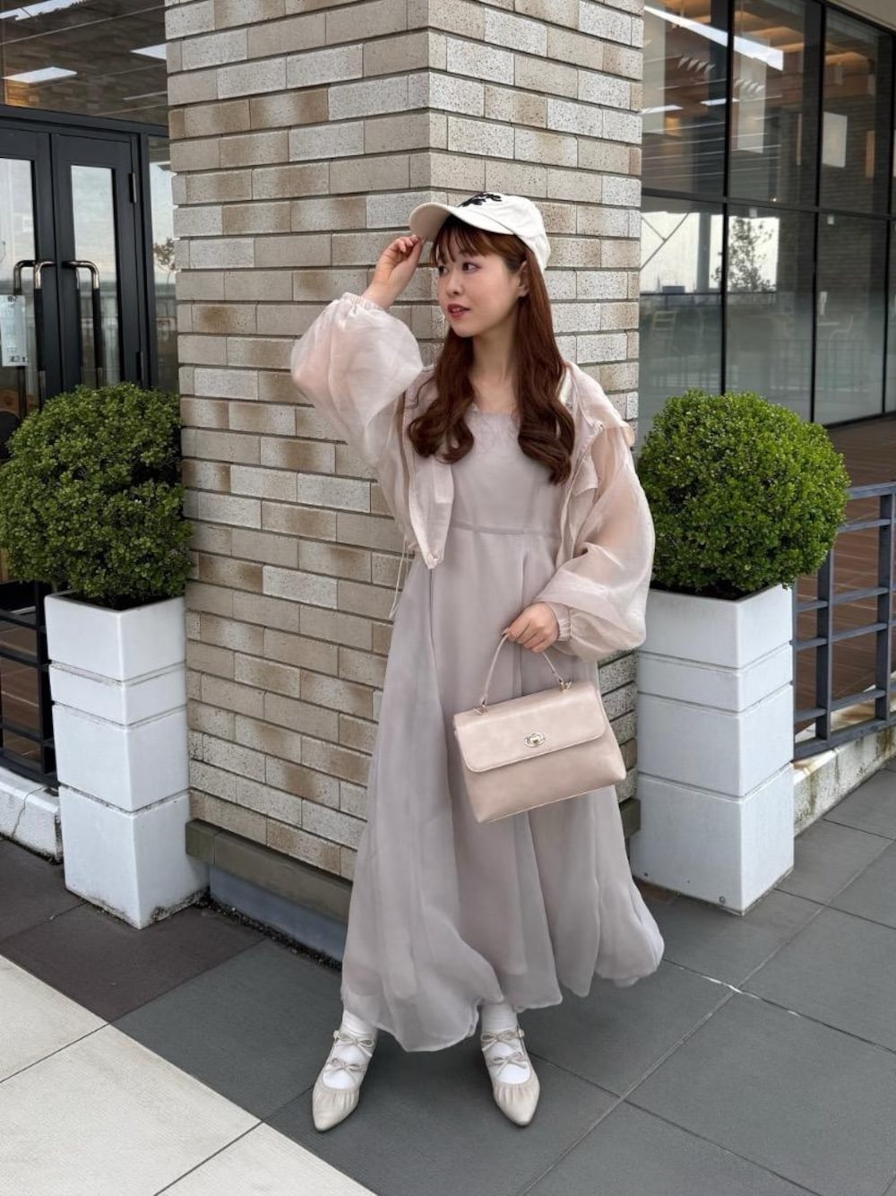 ホワイト系のパンプス、ベージュ系のワンピース、ピンク系のシャツ/ブラウスを着用したレディースの春コーディネートの1枚目の写真