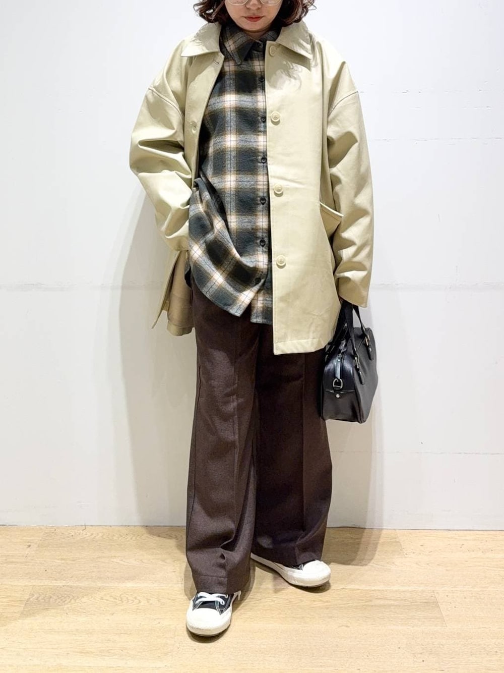 ベージュ系のステンカラーコート、ブラウン系のスラックス、グリーン系のシャツ/ブラウスを着用したレディースの秋コーディネートの1枚目の写真