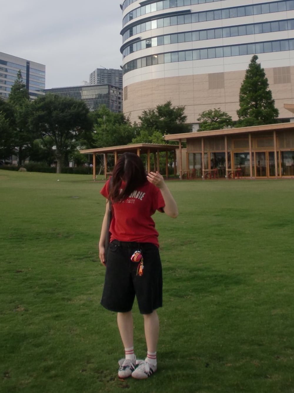 レッド系のTシャツ/カットソー、ブラック系のデニムパンツ、ホワイト系のスニーカーを着用したレディースの秋コーディネートの1枚目の写真