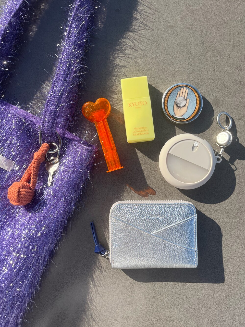 パープル系のトートバッグ、その他のキーホルダー、シルバー系の財布を着用したレディースの秋コーディネートの1枚目の写真