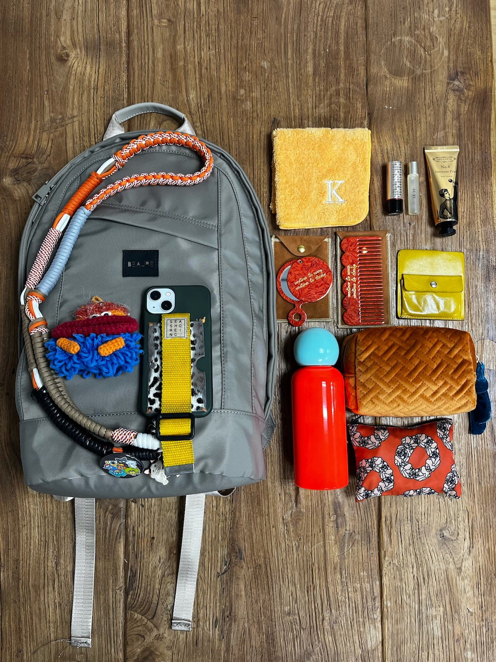 ベージュ系のバックパック/リュック、オレンジ系のスマホグッズ、グリーン系のスマホケース/カバーを着用したレディースの夏コーディネートの1枚目の写真