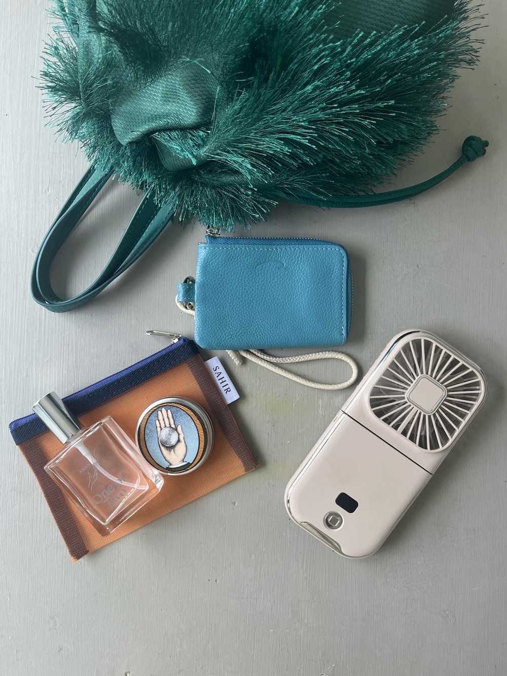 グリーン系のトートバッグ、ブルー系の財布、グレー系の香水を着用したレディースの夏コーディネートの1枚目の写真