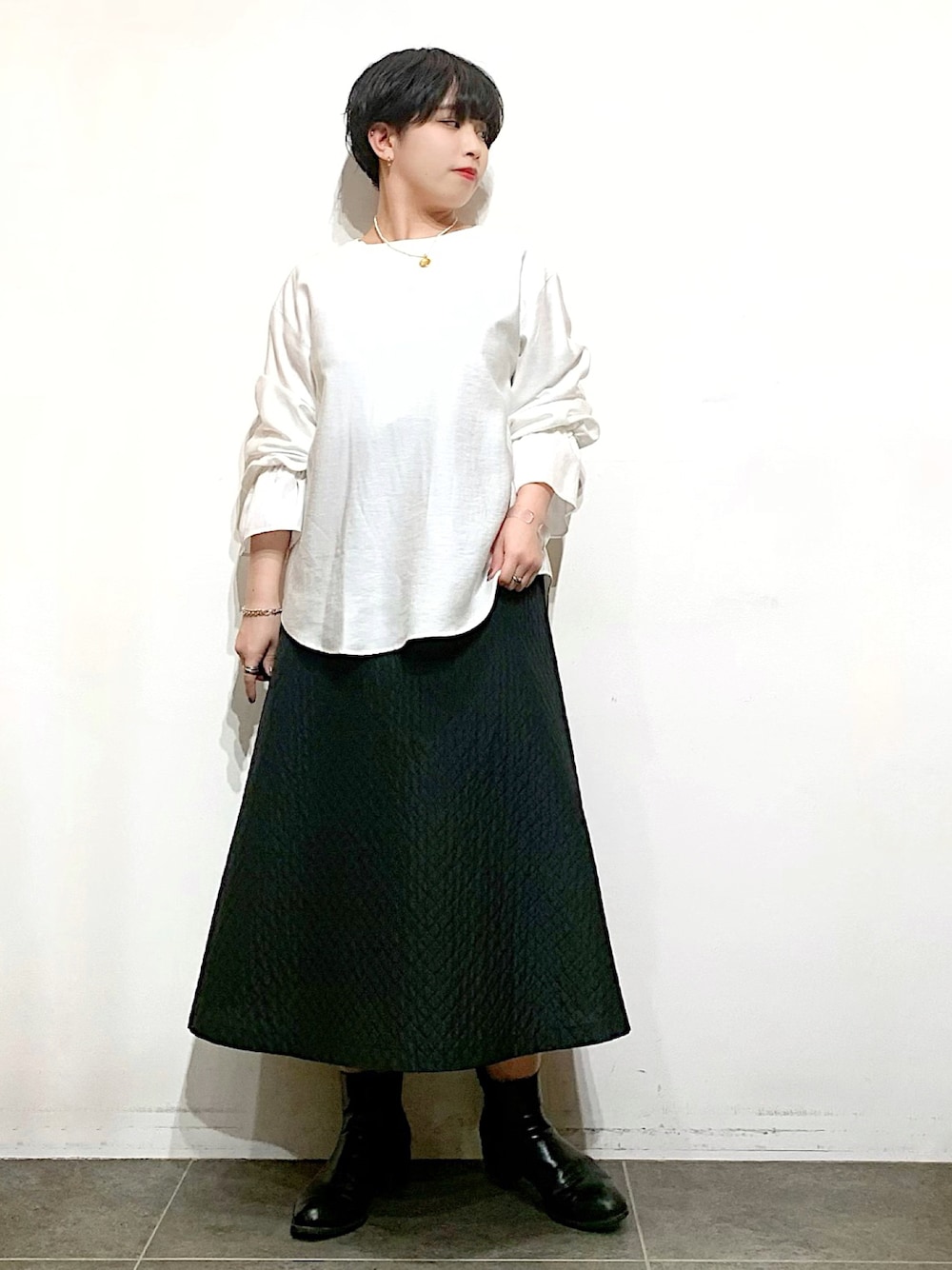 ブラック系のブーツ、ブラック系のスカート、ホワイト系のシャツ/ブラウスを着用したレディースの冬コーディネートの1枚目の写真