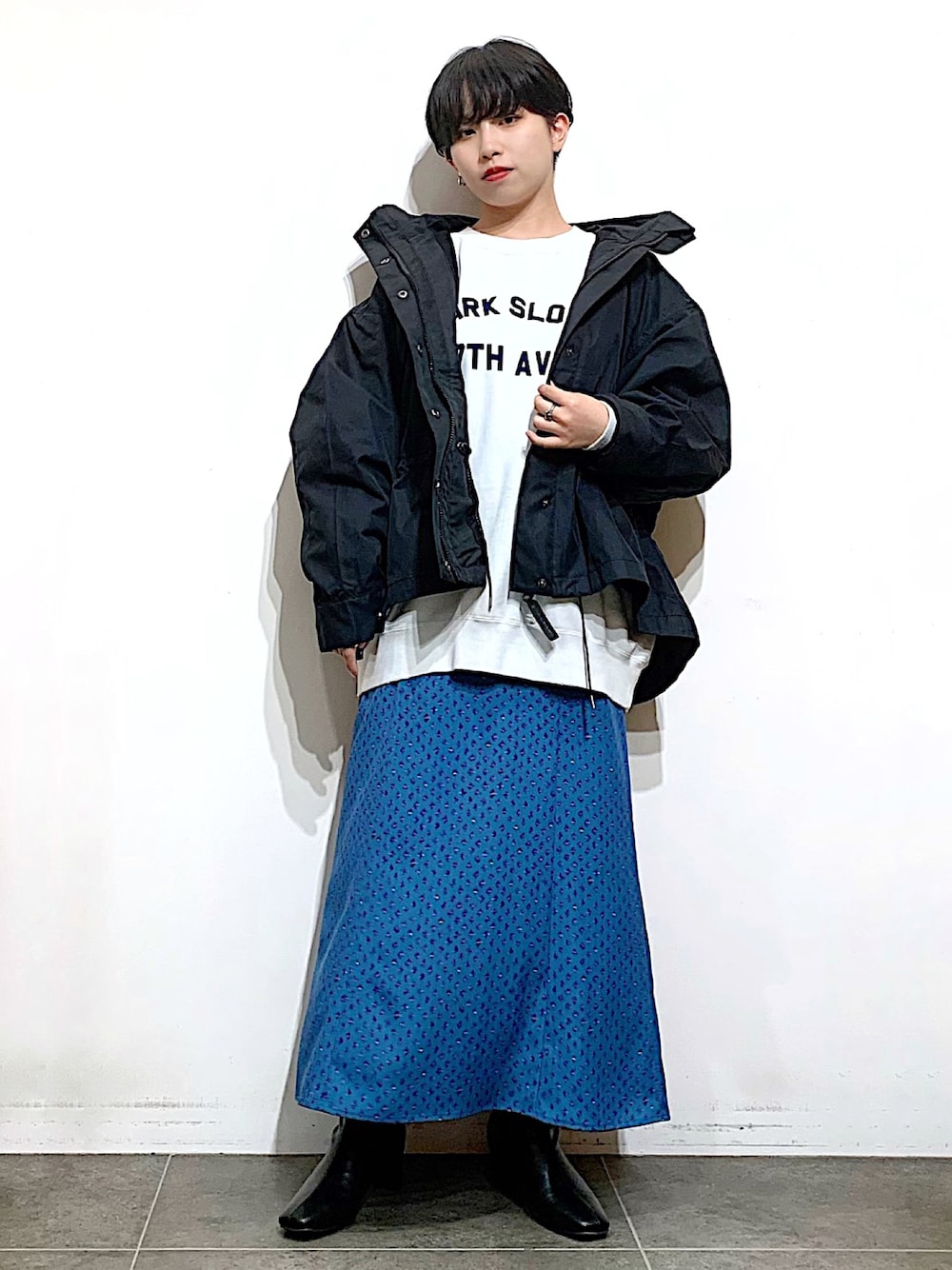 ブラック系のブーツ、ブルー系のスカート、ホワイト系のTシャツ/カットソーを着用したレディースの秋コーディネートの1枚目の写真