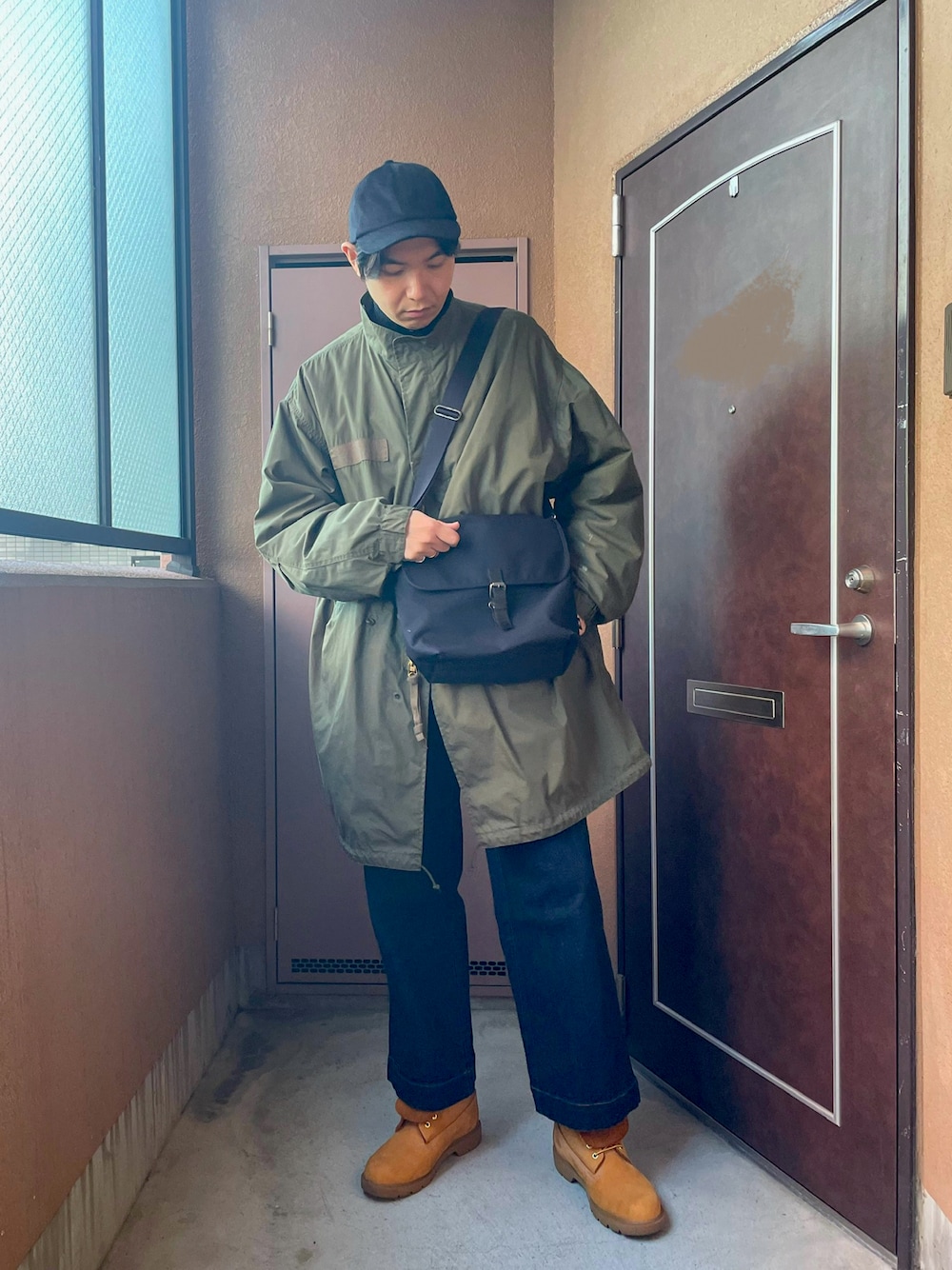 「ロングコート、冬アウター、M-65、モッズコート、カーキ、デニム、ブーツ、ミリタリー、カジュアル、キャップ、UNIQLO、ショルダーバッグ、モックネック、レイヤードスタイル、オトナカジュアル」｜「MBのアイテム（デニムパンツ、ブルー系）」を使った、MKさん（メンズ・185cm）の冬コーディネートの1枚目の写真