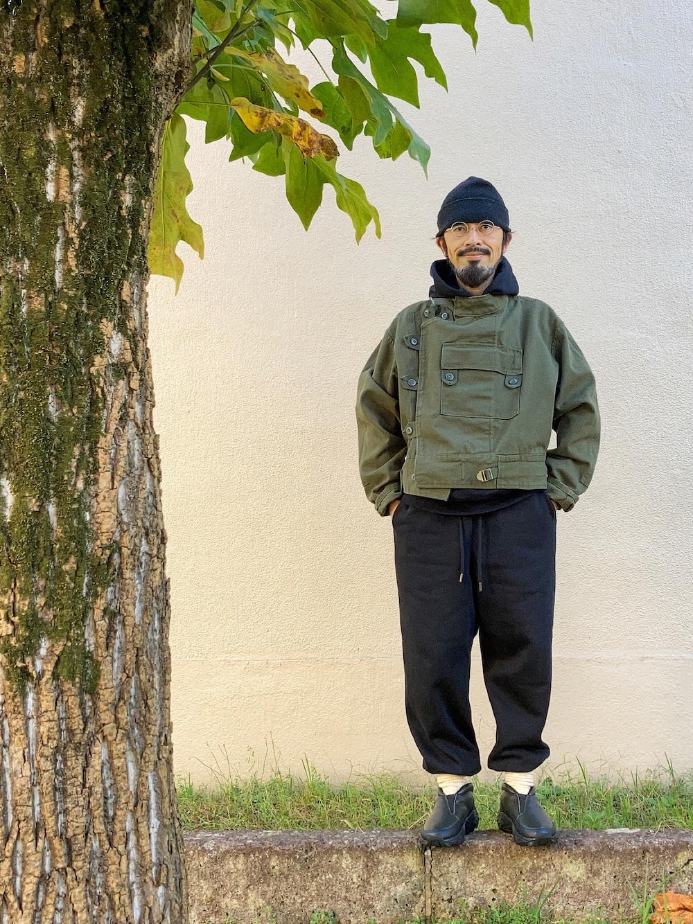 ブラック系のパーカー、グリーン系のミリタリージャケット、ブラック系のスウェットパンツを着用したメンズの秋コーディネートの1枚目の写真