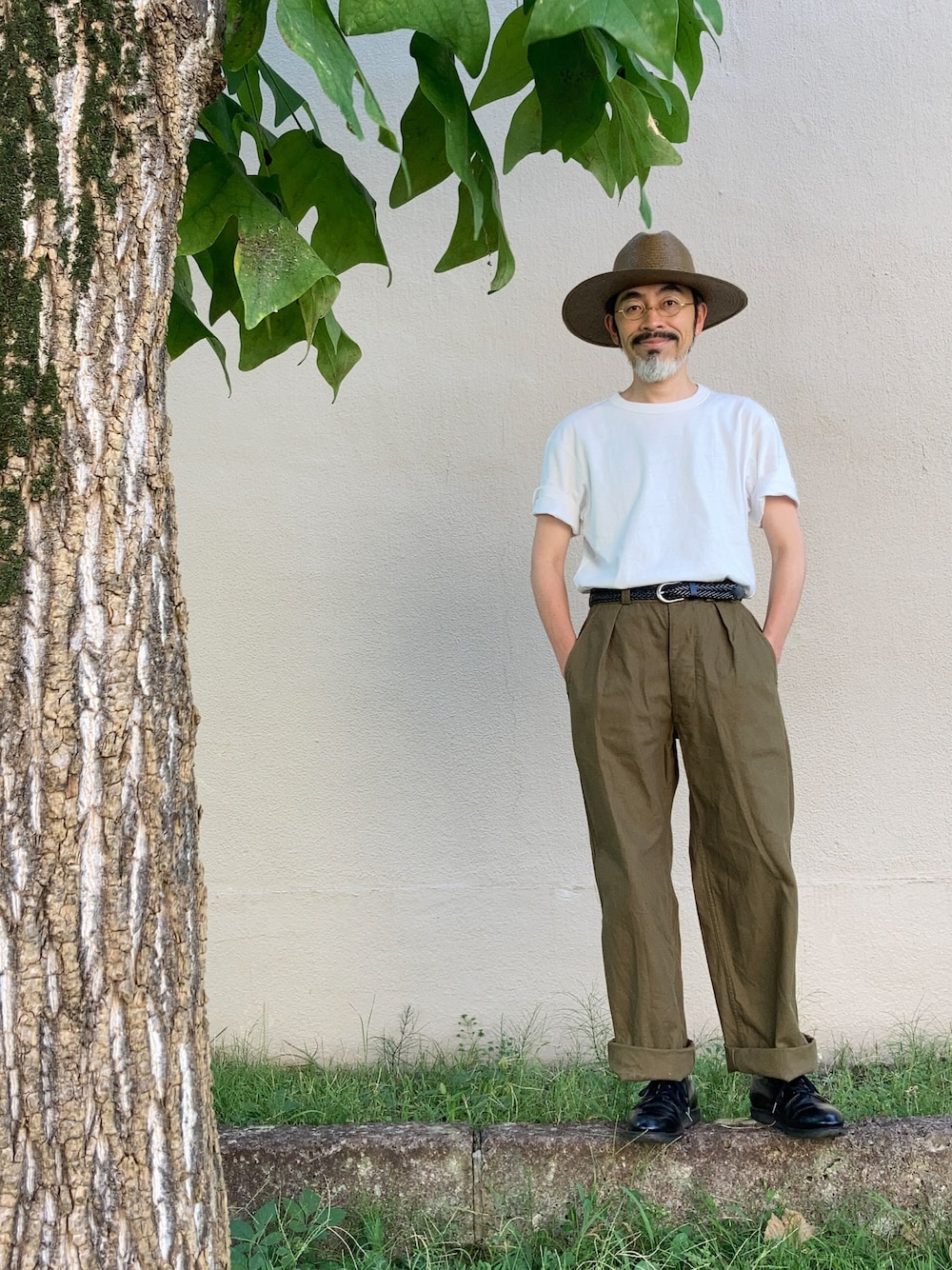 ホワイト系のTシャツ/カットソー、グリーン系のスラックス、ブラック系のドレスシューズを着用したメンズの夏コーディネートの1枚目の写真