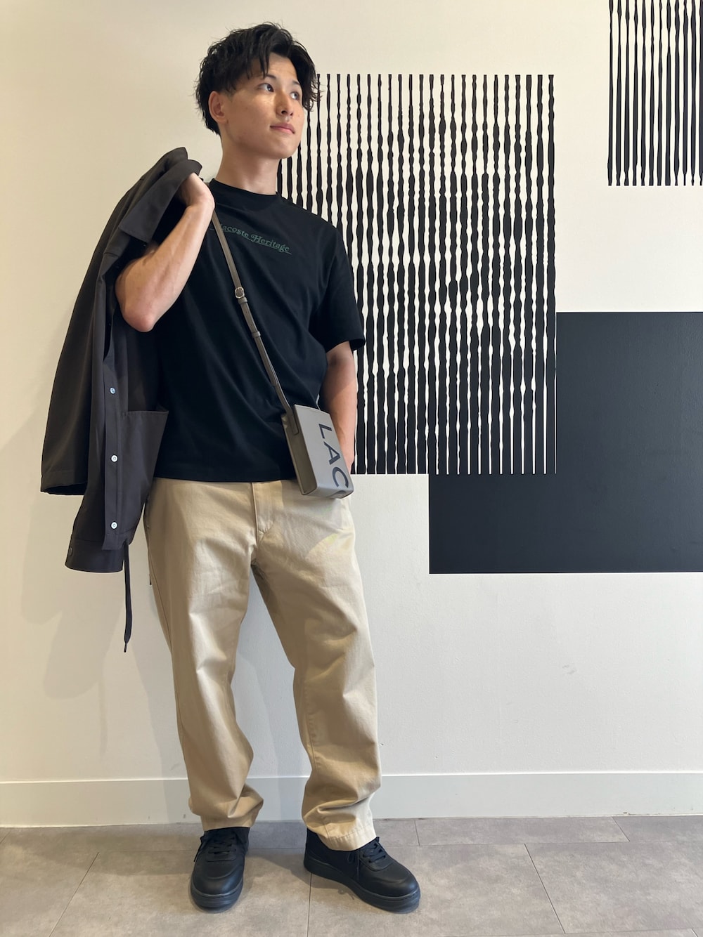 ブラック系のTシャツ/カットソー、ベージュ系のチノパンツ、ブラック系のスニーカーを着用したメンズの秋コーディネートの1枚目の写真