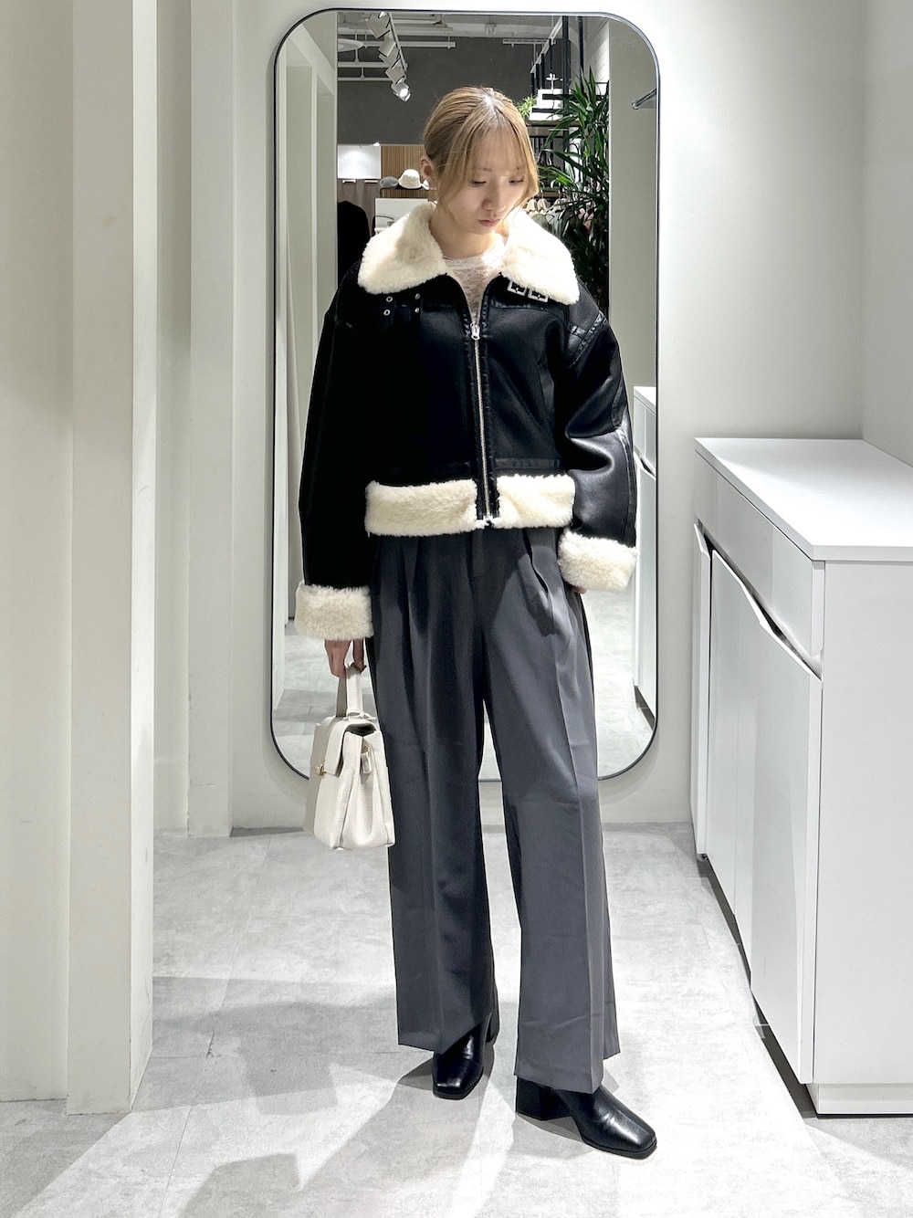 ブラック系のブルゾン、ブラック系のブーツ、グレー系のスラックスを着用したレディースの秋コーディネートの1枚目の写真