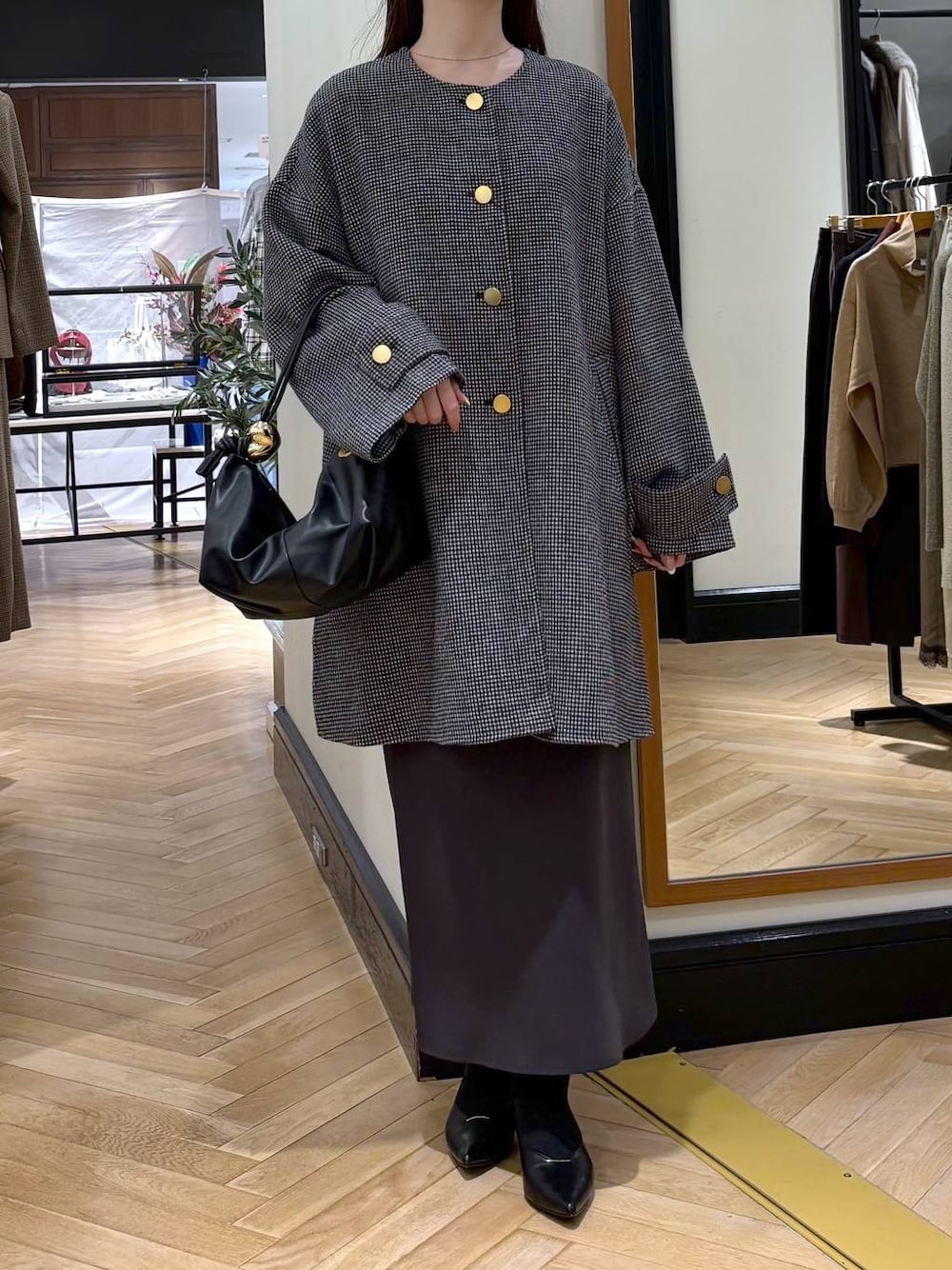 グレー系のスカート、ブラック系のパンプス、その他のノーカラーコートを着用したレディースの秋コーディネートの1枚目の写真