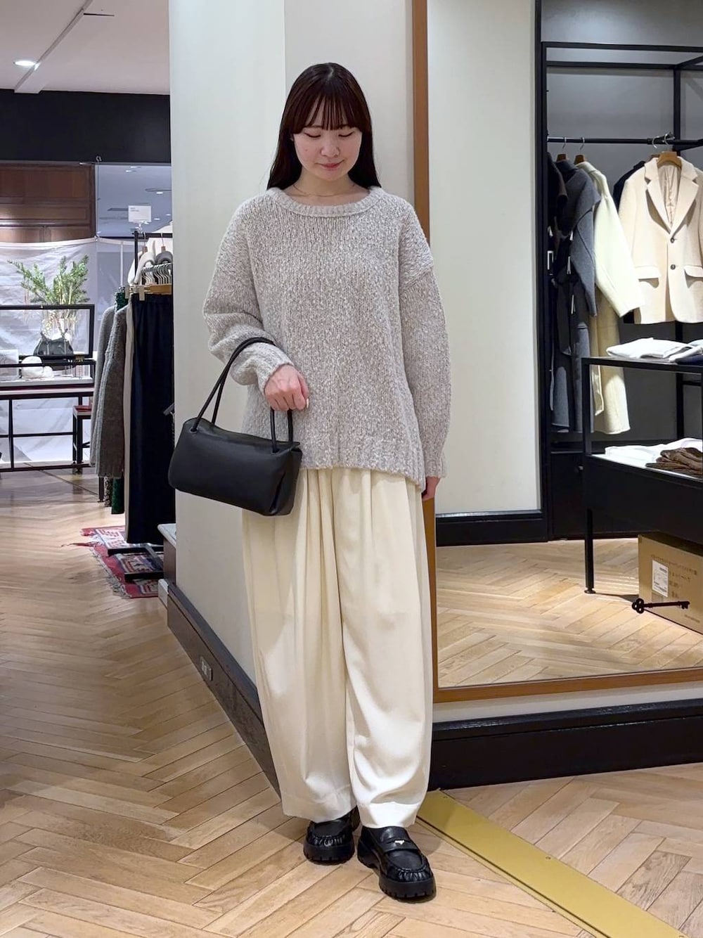 ホワイト系のスラックス、ブラック系のローファー、グレー系のニット/セーターを着用したレディースの冬コーディネートの1枚目の写真