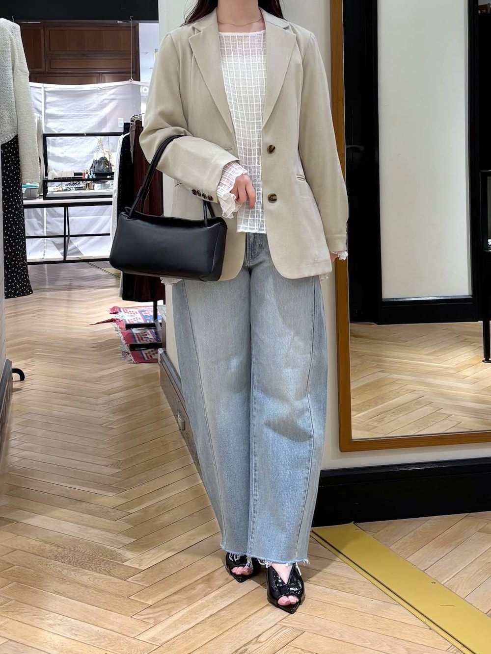 ブルー系のデニムパンツ、ベージュ系のノーカラージャケット、ブラック系のショルダーバッグを着用したレディースの春コーディネートの1枚目の写真