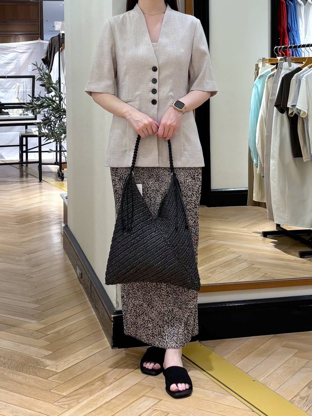 ベージュ系のスカート、ベージュ系のノーカラージャケット、ブラック系のサンダルを着用したレディースの春コーディネートの1枚目の写真