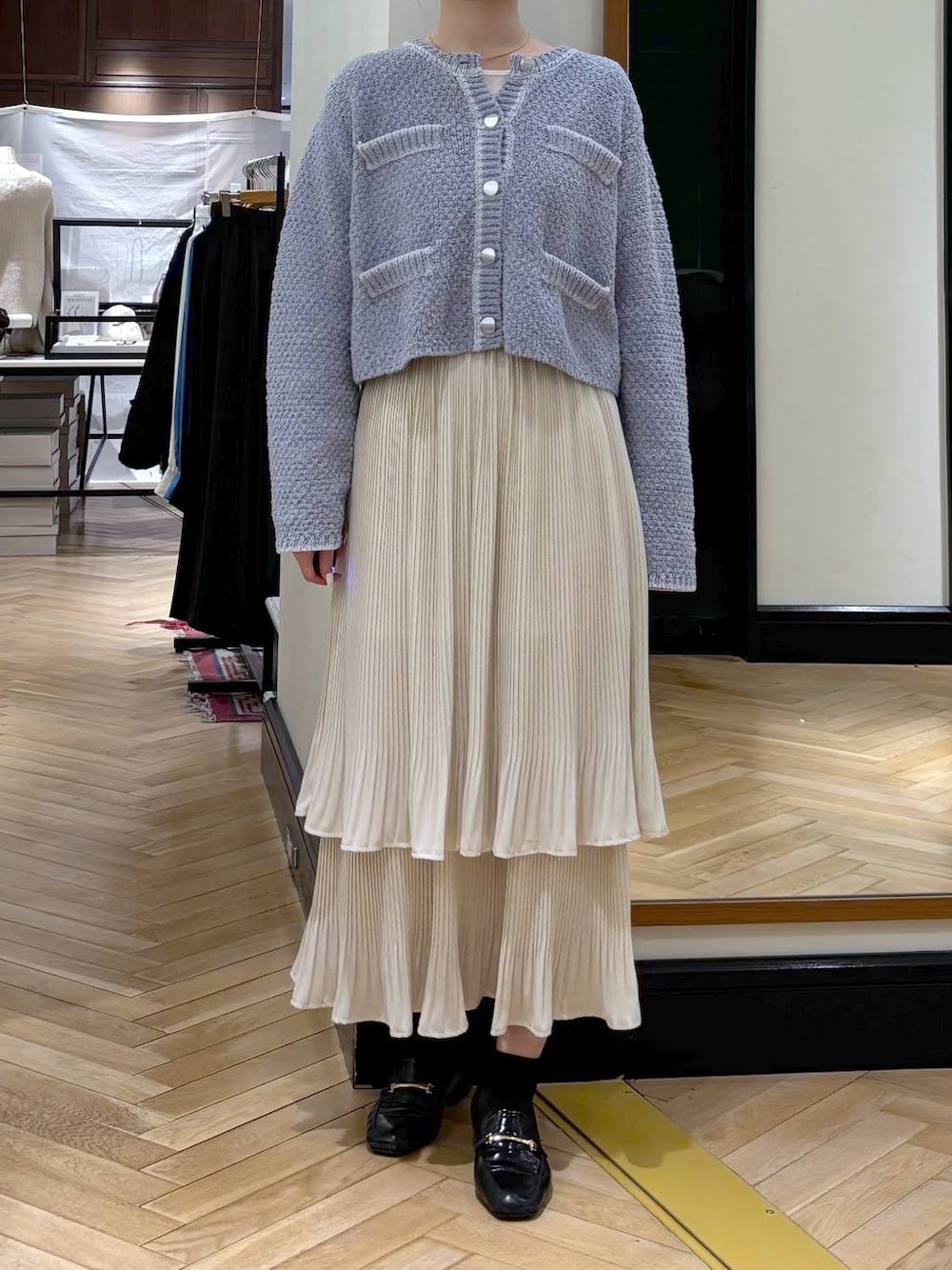 ホワイト系のスカート、ブラック系のローファー、ブルー系のカーディガン/ボレロを着用したレディースの冬コーディネートの1枚目の写真