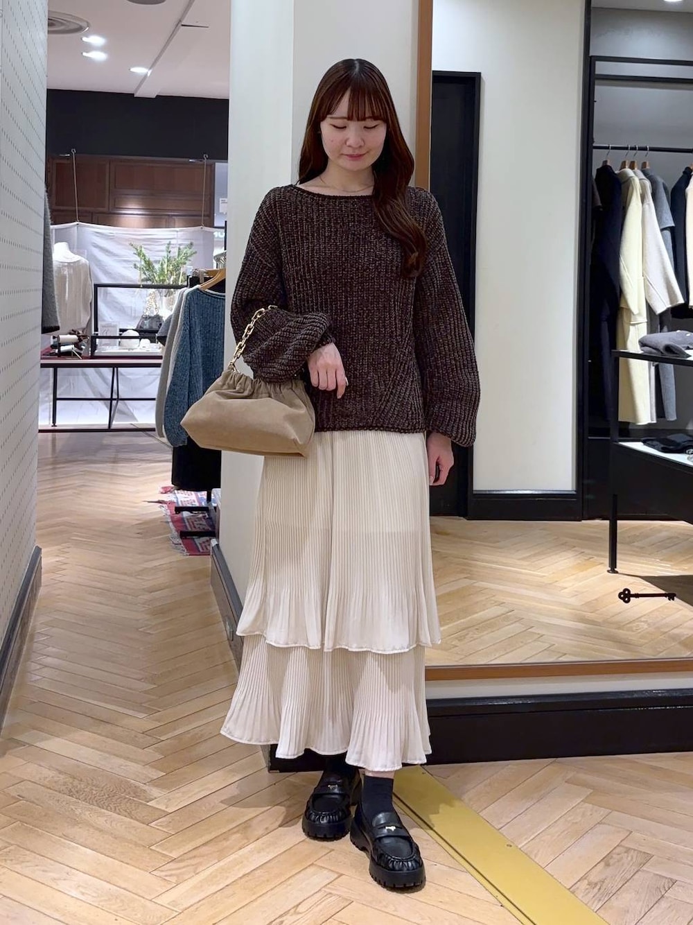 ホワイト系のスカート、ブラウン系のニット/セーター、ベージュ系のショルダーバッグを着用したレディースの冬コーディネートの1枚目の写真