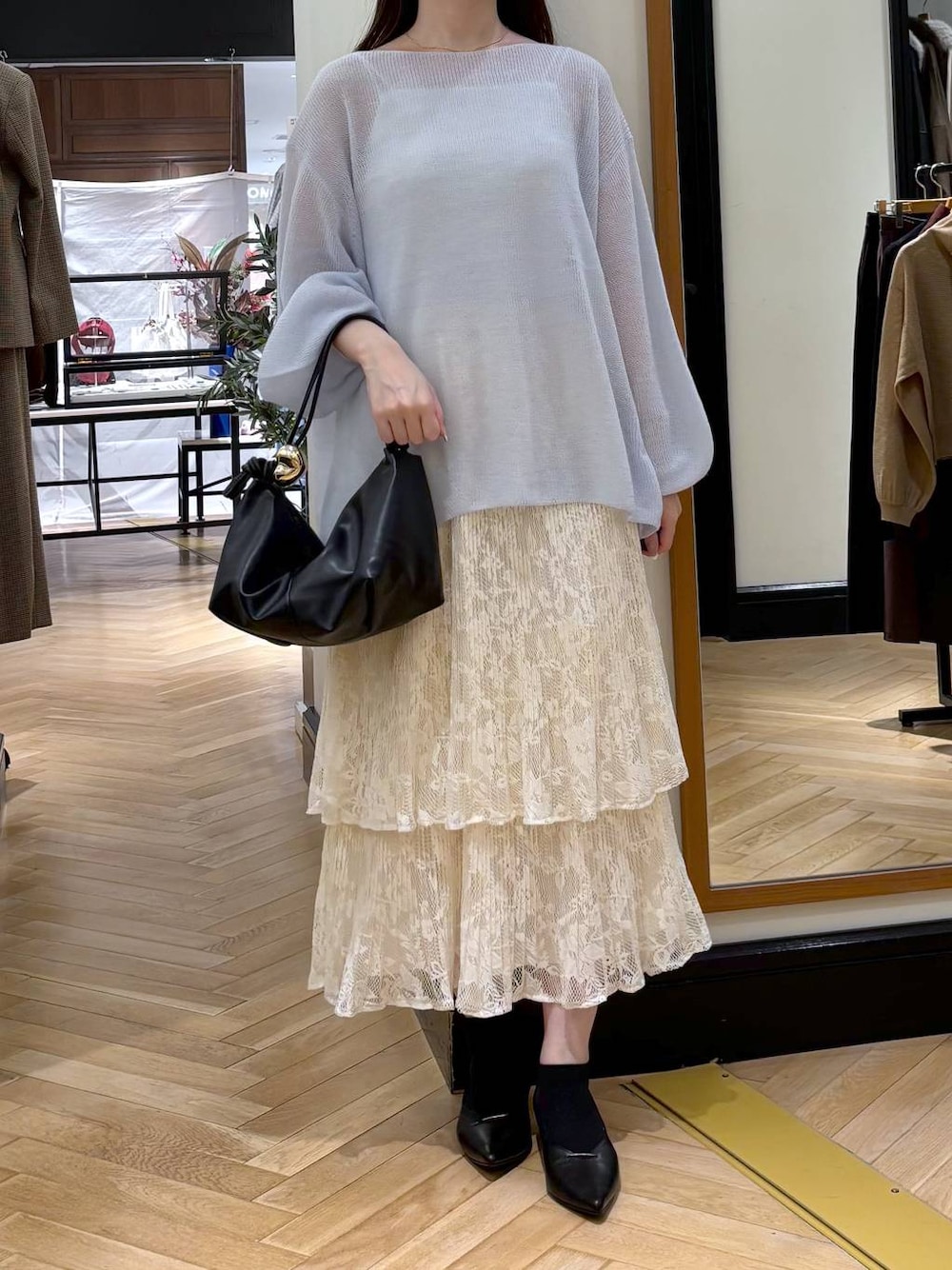 ブラック系のパンプス、ホワイト系のスカート、ブラック系のショルダーバッグを着用したレディースの秋コーディネートの1枚目の写真