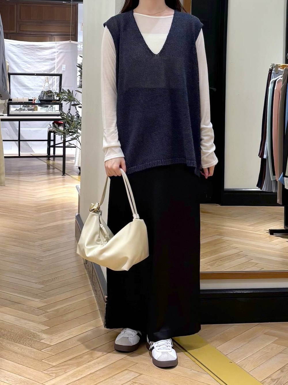 ブラック系のスカート、ブルー系のニット/セーター、ベージュ系のショルダーバッグを着用したレディースの春コーディネートの1枚目の写真