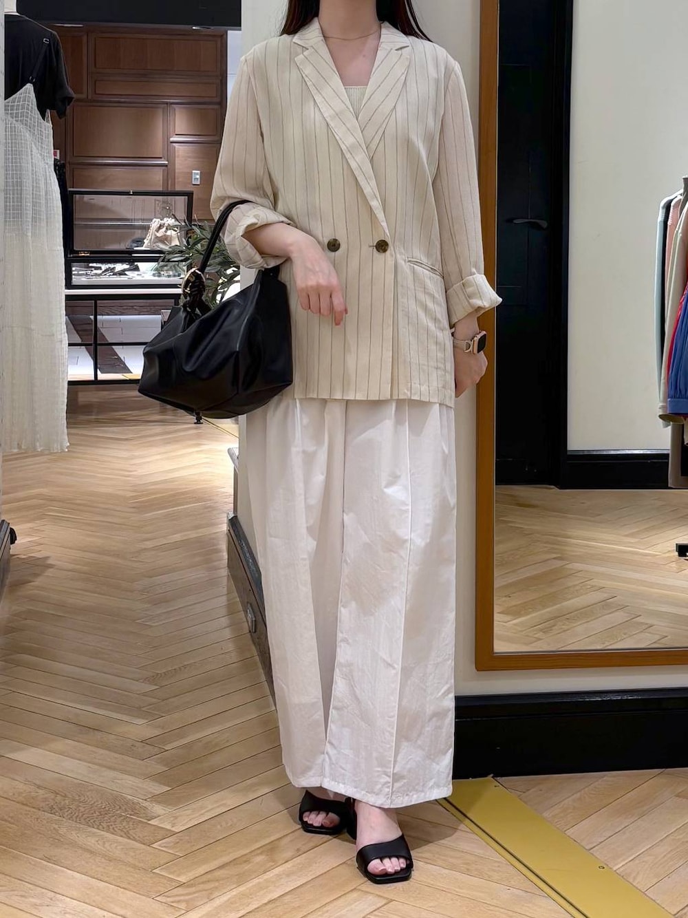 ベージュ系のテーラードジャケット、ブラック系のショルダーバッグ、ホワイト系のタンクトップを着用したレディースの春コーディネートの1枚目の写真