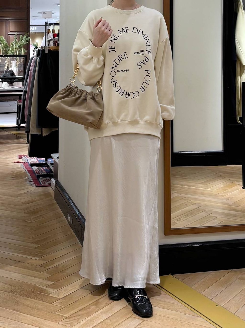 ブラック系のローファー、ホワイト系のスカート、ベージュ系のショルダーバッグを着用したレディースの冬コーディネートの1枚目の写真