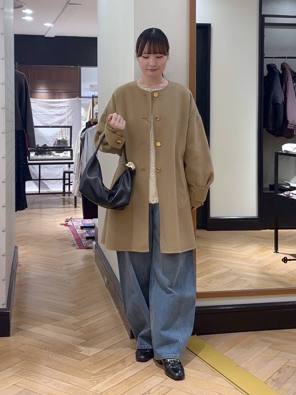 ブルー系のデニムパンツ、ベージュ系のノーカラーコート、ブラック系のショルダーバッグを着用したレディースの秋コーディネートの1枚目の写真