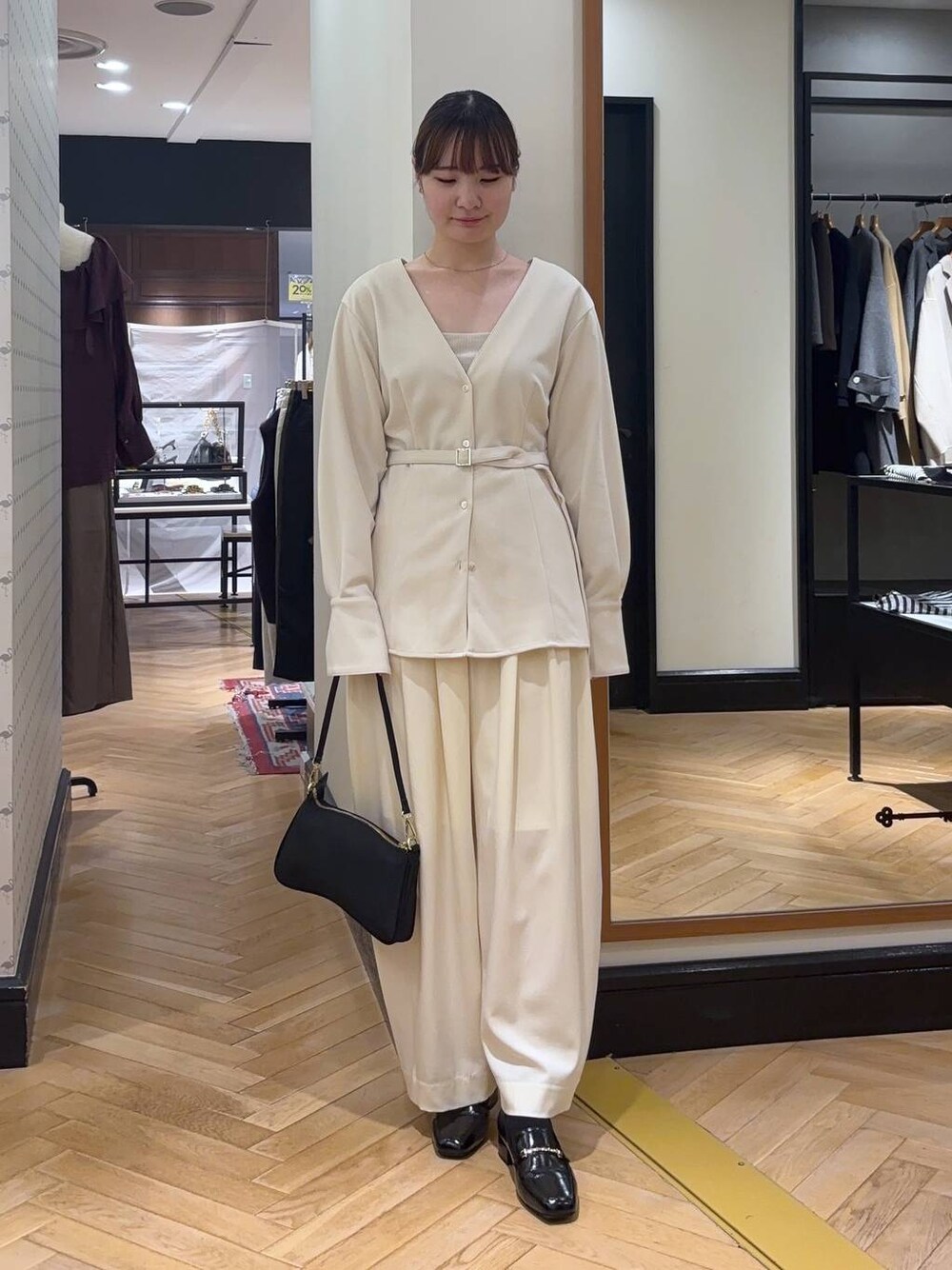 ホワイト系のスラックス、ブラック系のローファー、ブラック系のショルダーバッグを着用したレディースの秋コーディネートの1枚目の写真