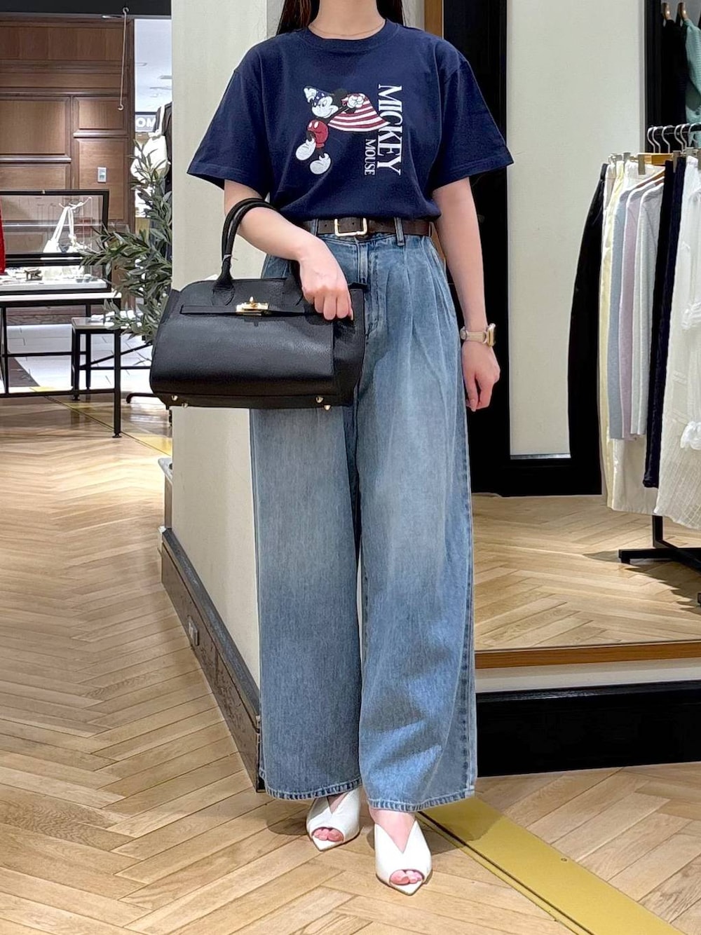ブラック系のショルダーバッグ、ブルー系のデニムパンツ、ホワイト系のサンダルを着用したレディースの春コーディネートの1枚目の写真