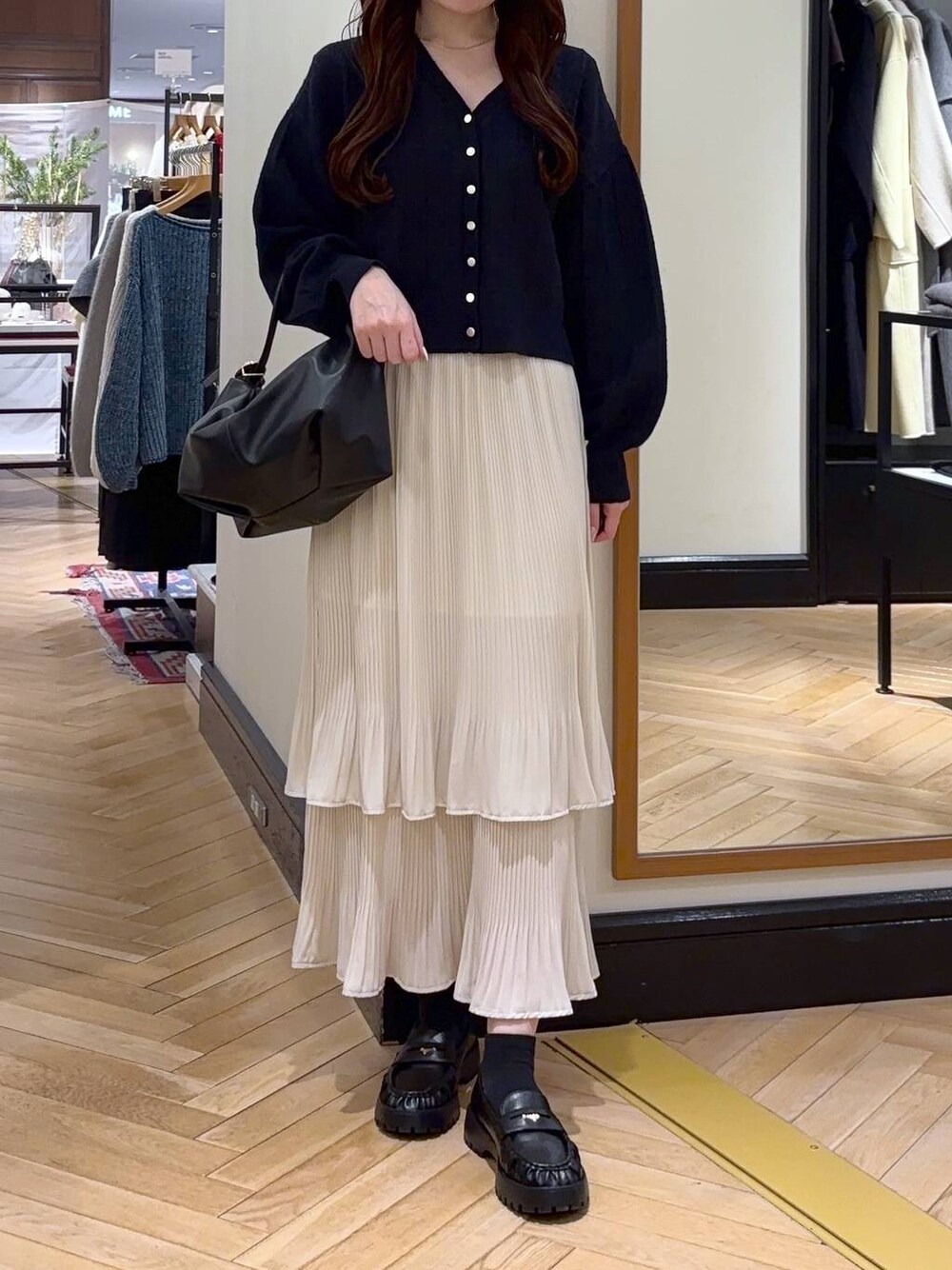 ホワイト系のスカート、ブラック系のショルダーバッグ、ブルー系のカーディガン/ボレロを着用したレディースの冬コーディネートの1枚目の写真