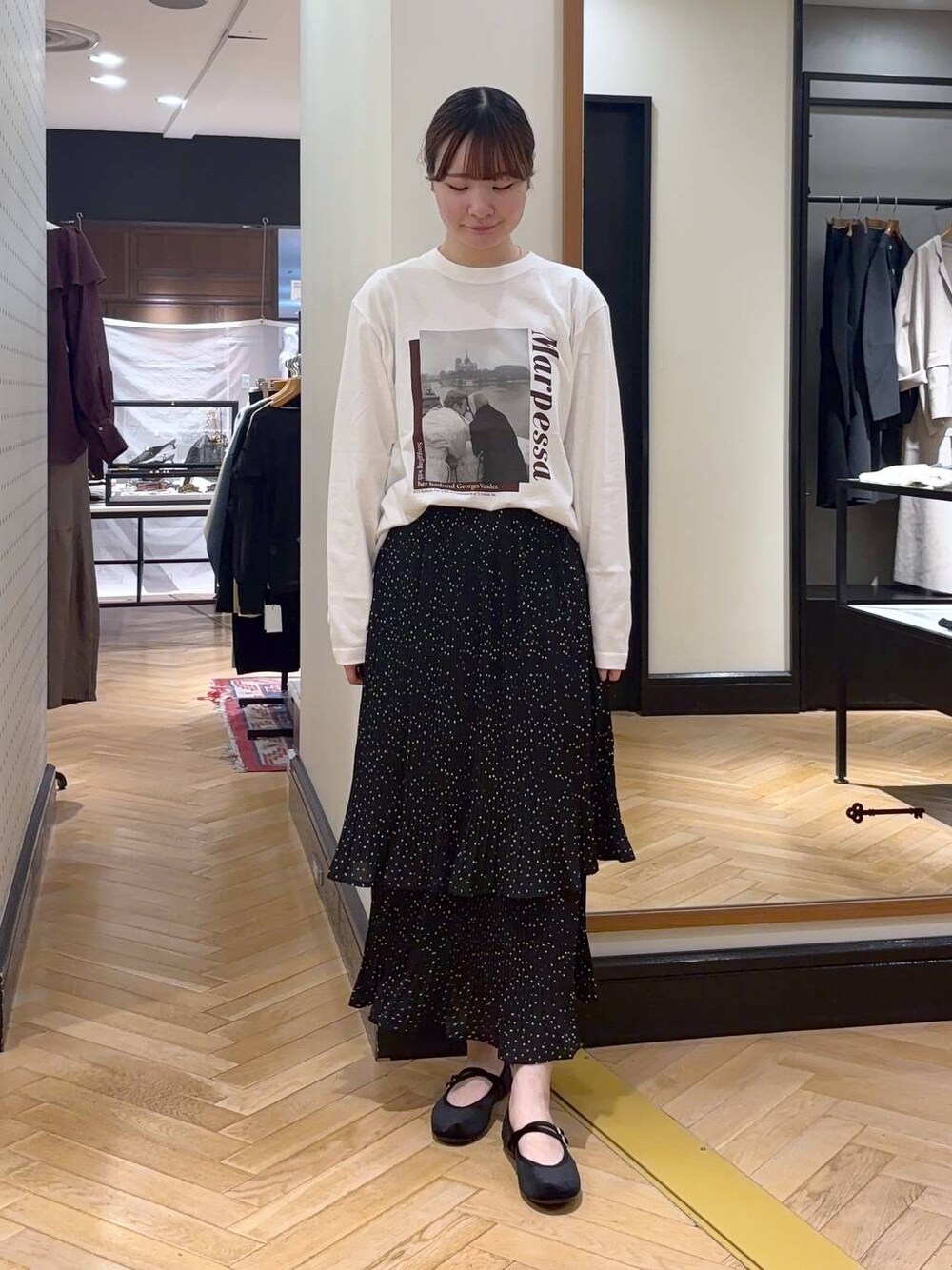 グレー系のスカート、ブラック系のバレエシューズ、ホワイト系のTシャツ/カットソーを着用したレディースの秋コーディネートの1枚目の写真