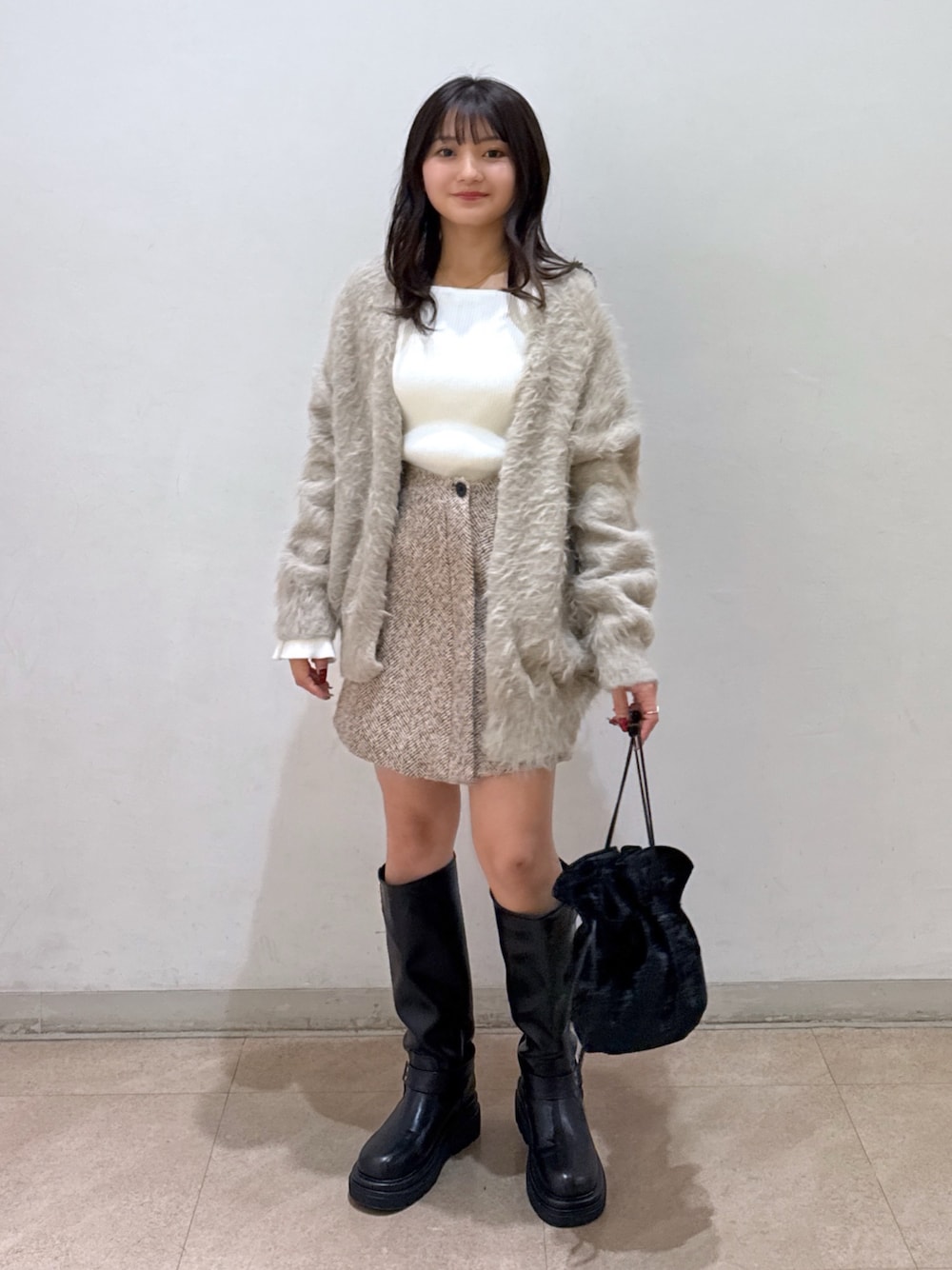 ベージュ系のカーディガン/ボレロ、ホワイト系のニット/セーター、ベージュ系のスカートを着用したレディースの冬コーディネートの1枚目の写真