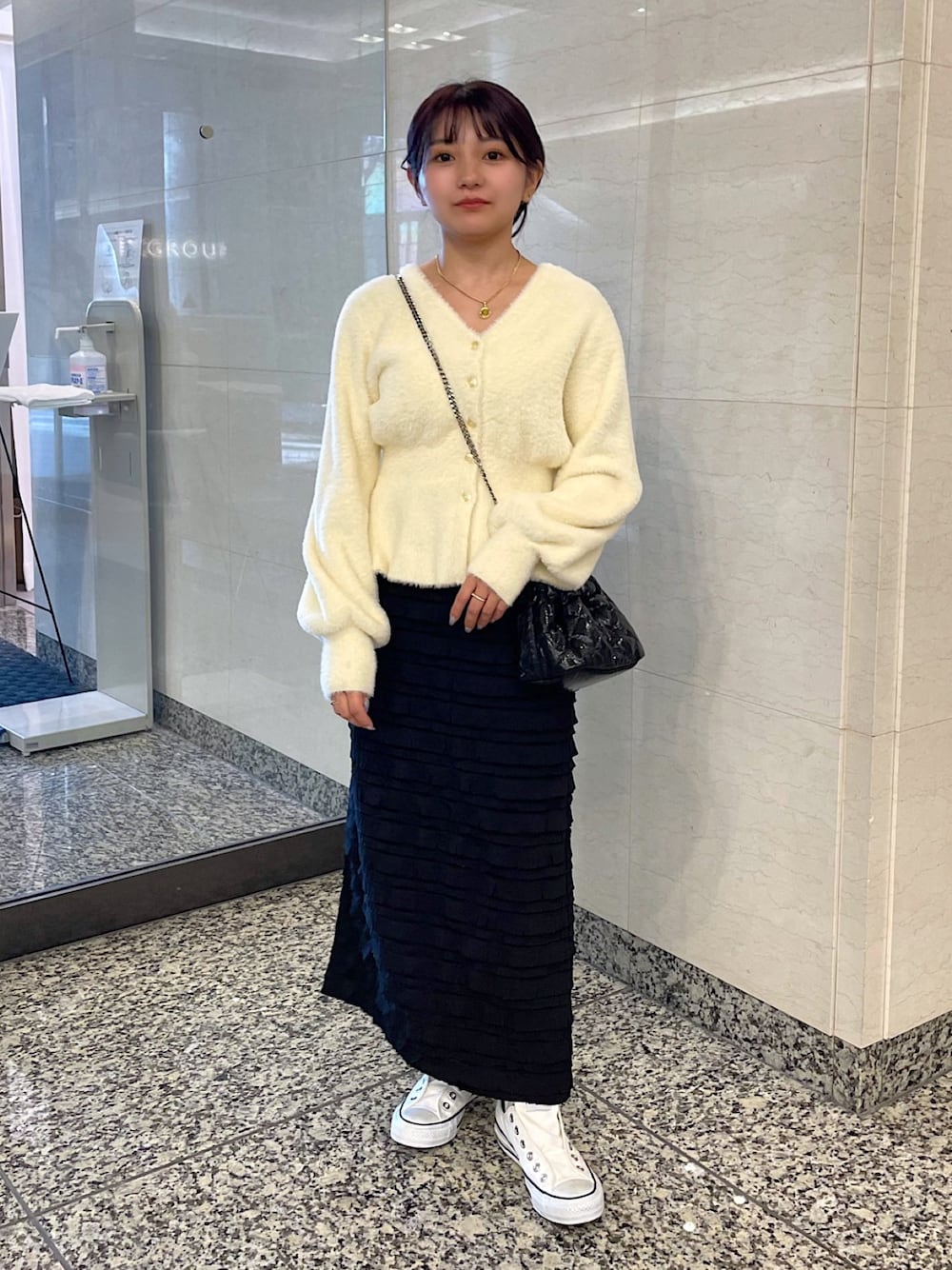 ホワイト系のカーディガン/ボレロ、ブラック系のスカート、ブラック系のショルダーバッグを着用したレディースの冬コーディネートの1枚目の写真