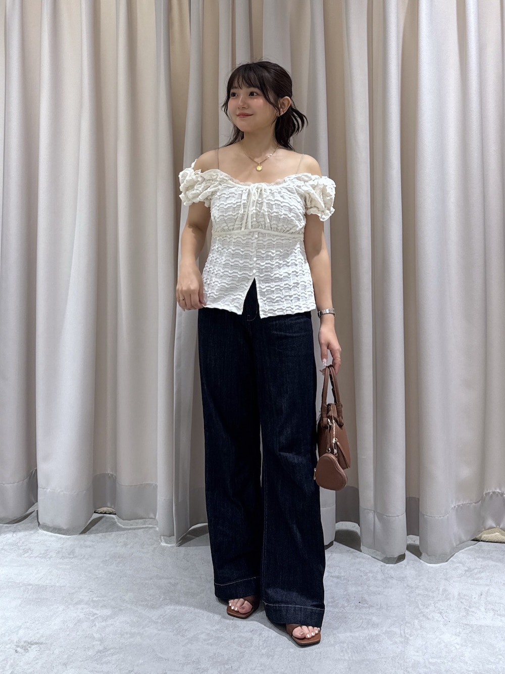 ブラウン系のサンダル、ブルー系のデニムパンツ、ブラウン系のボストンバッグを着用したレディースの夏コーディネートの1枚目の写真