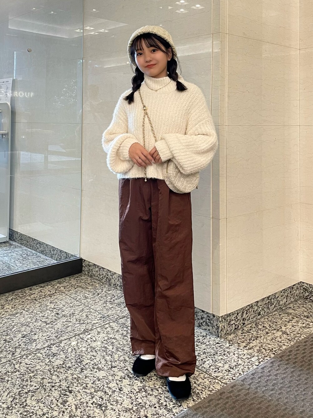 ホワイト系のニット/セーター、ブラウン系のその他パンツ、ベージュ系のショルダーバッグを着用したレディースの秋コーディネートの1枚目の写真