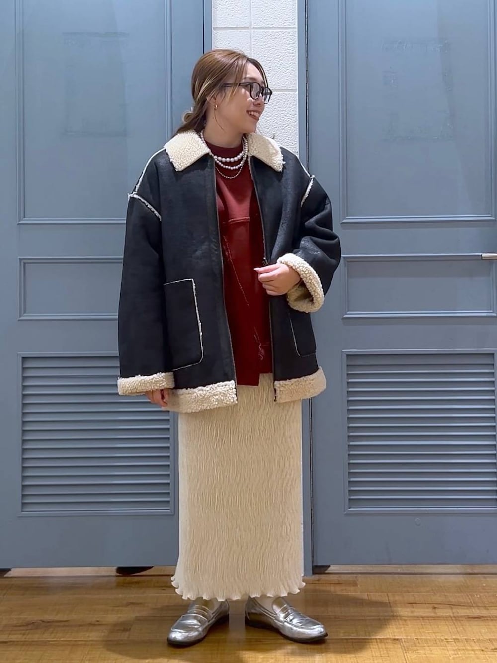 ブラック系のブルゾン、ホワイト系のスカート、シルバー系のローファーを着用したレディースの冬コーディネートの1枚目の写真