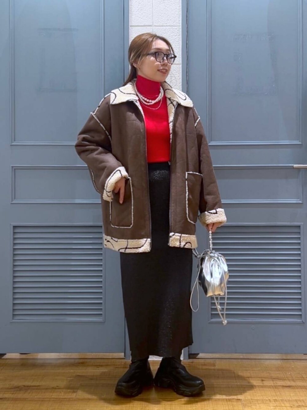 ブラウン系のブルゾン、レッド系のニット/セーター、シルバー系のショルダーバッグを着用したレディースの冬コーディネートの1枚目の写真