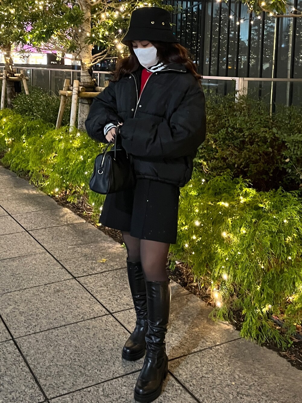 ブラック系のダウンジャケット/コート、ブラック系のTシャツ/カットソー、ブラック系のブーツを着用したレディースの冬コーディネートの1枚目の写真