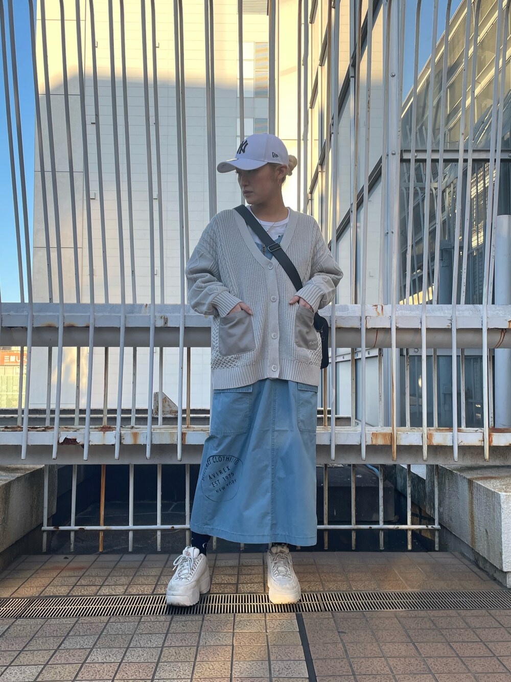 ブルー系のジャンパースカート、グレー系のカーディガン/ボレロ、ホワイト系のTシャツ/カットソーを着用したレディースの冬コーディネートの1枚目の写真