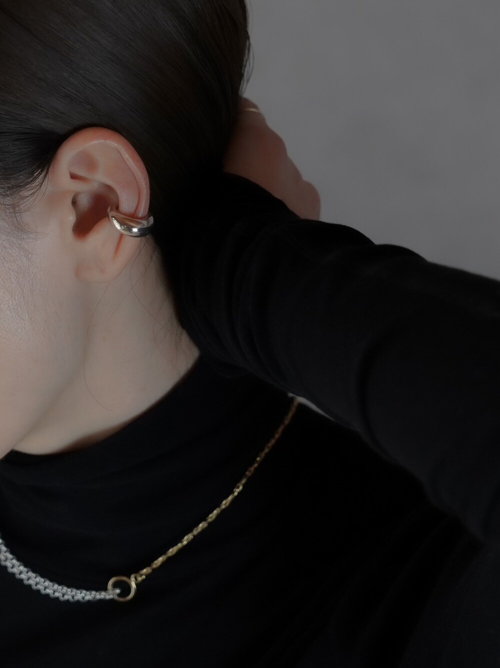 シルバー系のイヤーカフ、シルバー系のネックレスを着用したレディースの冬コーディネートの1枚目の写真