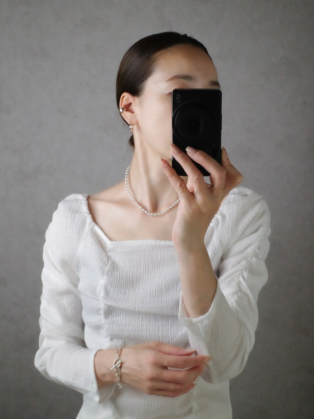 ホワイト系のネックレス、シルバー系のブレスレット、シルバー系のピアス（両耳用）を着用したレディースの秋コーディネートの1枚目の写真