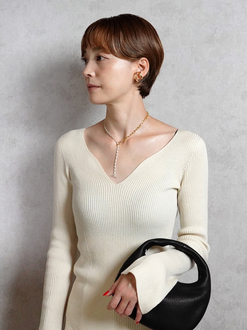 ブラック系のバッグ、シルバー系のネックレス、ゴールド系のイヤーカフを着用したレディースの秋コーディネートの1枚目の写真