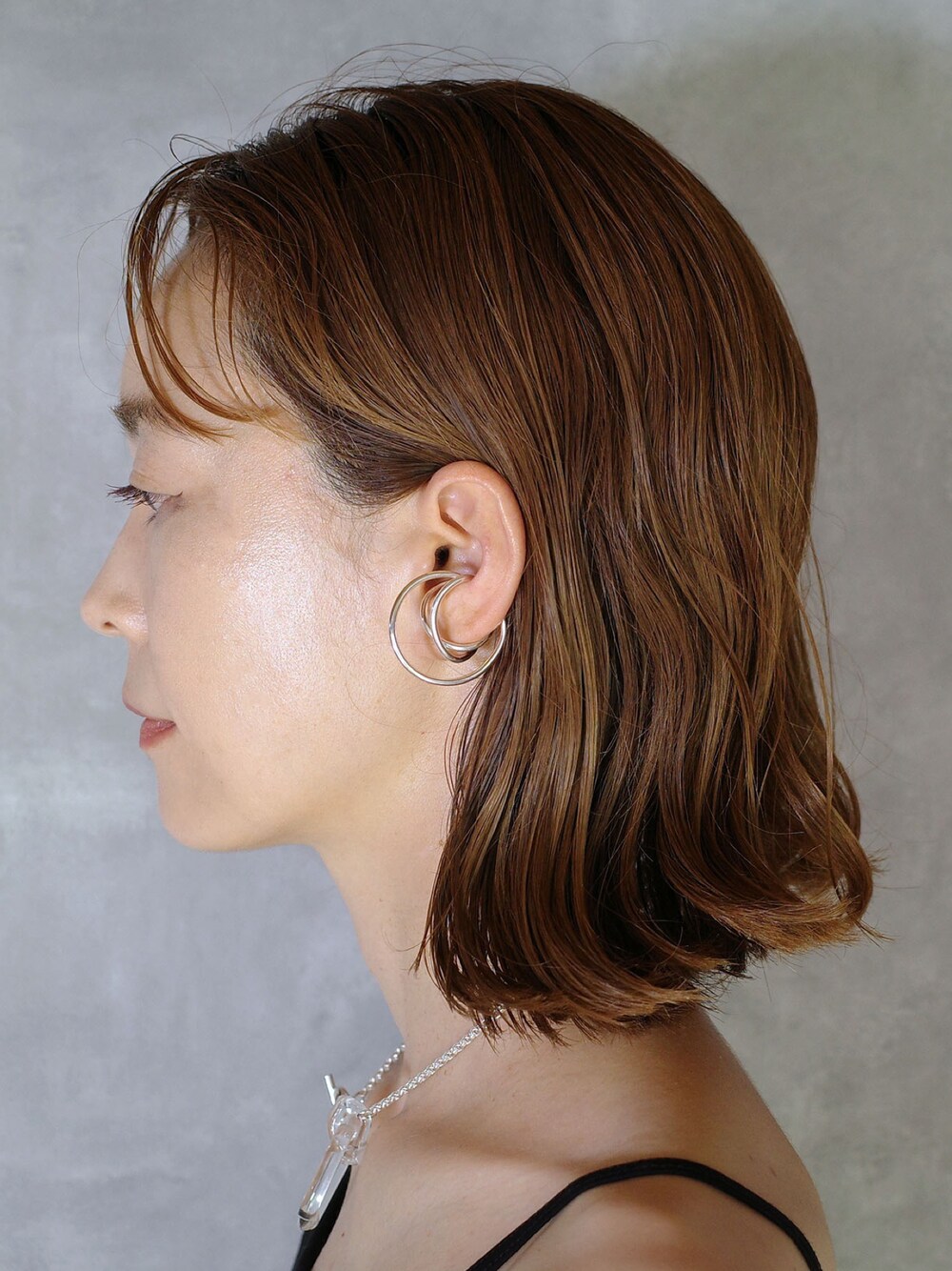 シルバー系のイヤーカフ、シルバー系のネックレスを着用したレディースの夏コーディネートの1枚目の写真